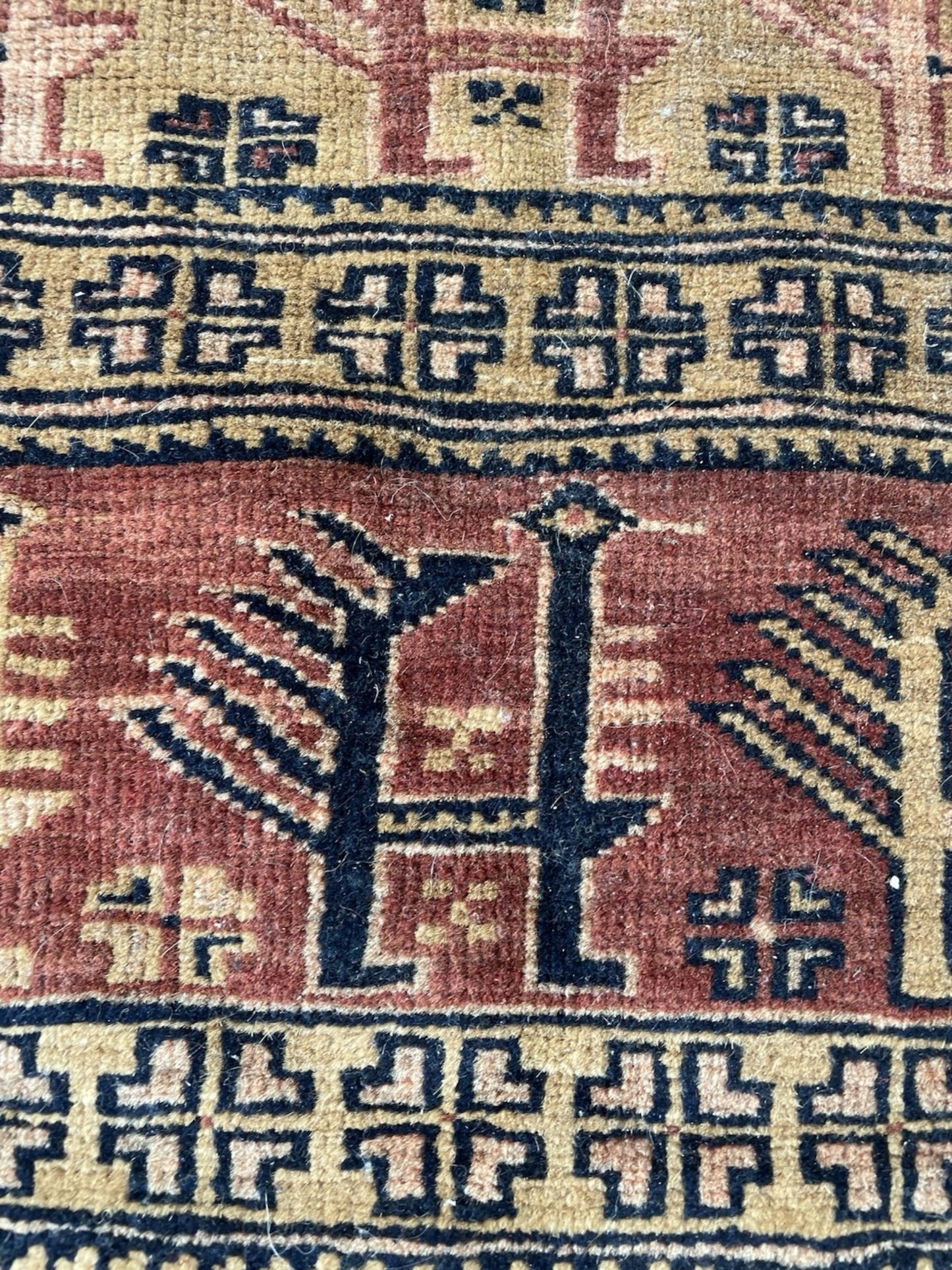 Close-up detail of the interconnected tribal motifs on the terracotta field.

