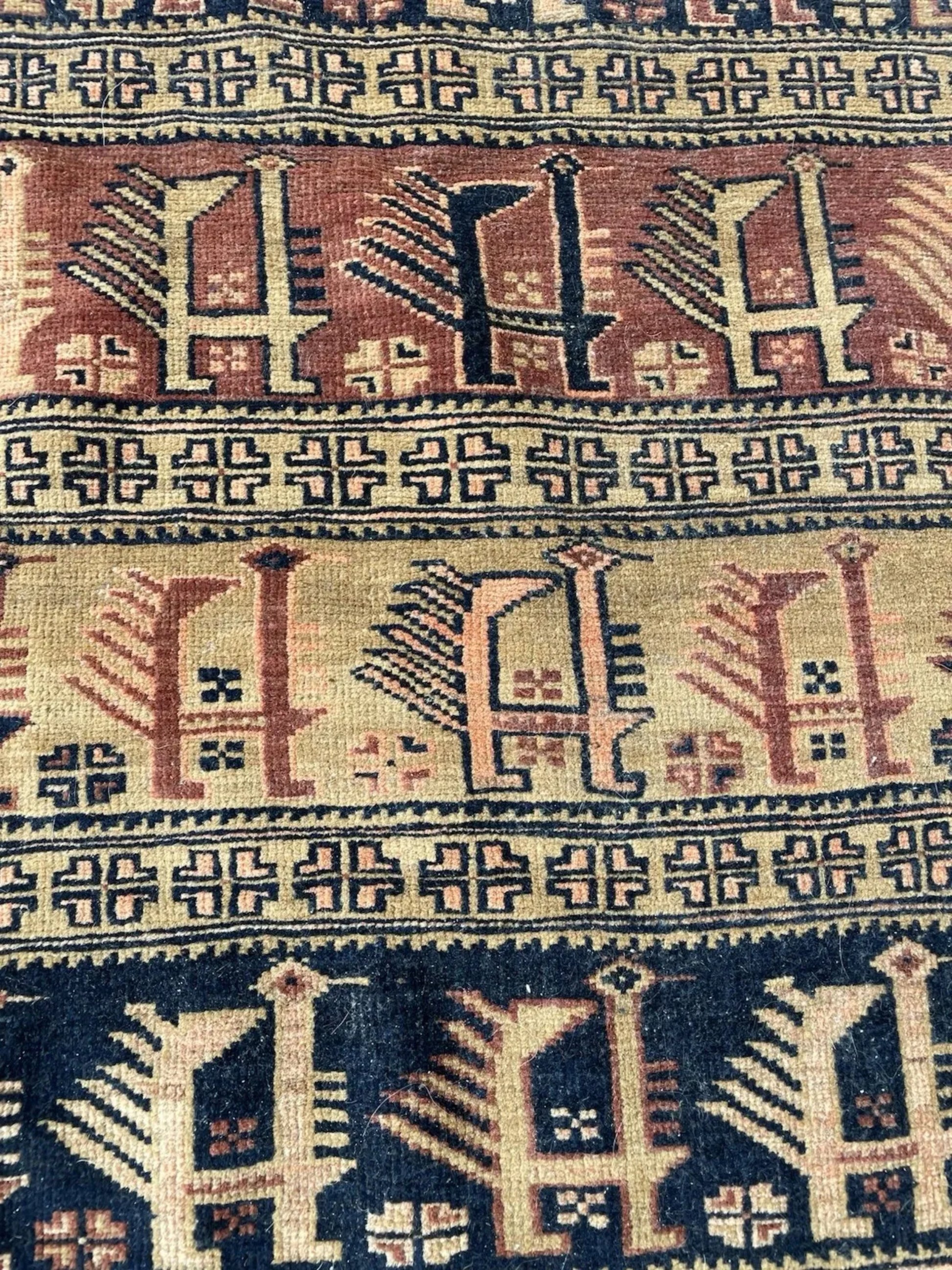 Antique Afghan Baluch rug center medallion close-up showcasing deep red field and navy blue geometric motifs
