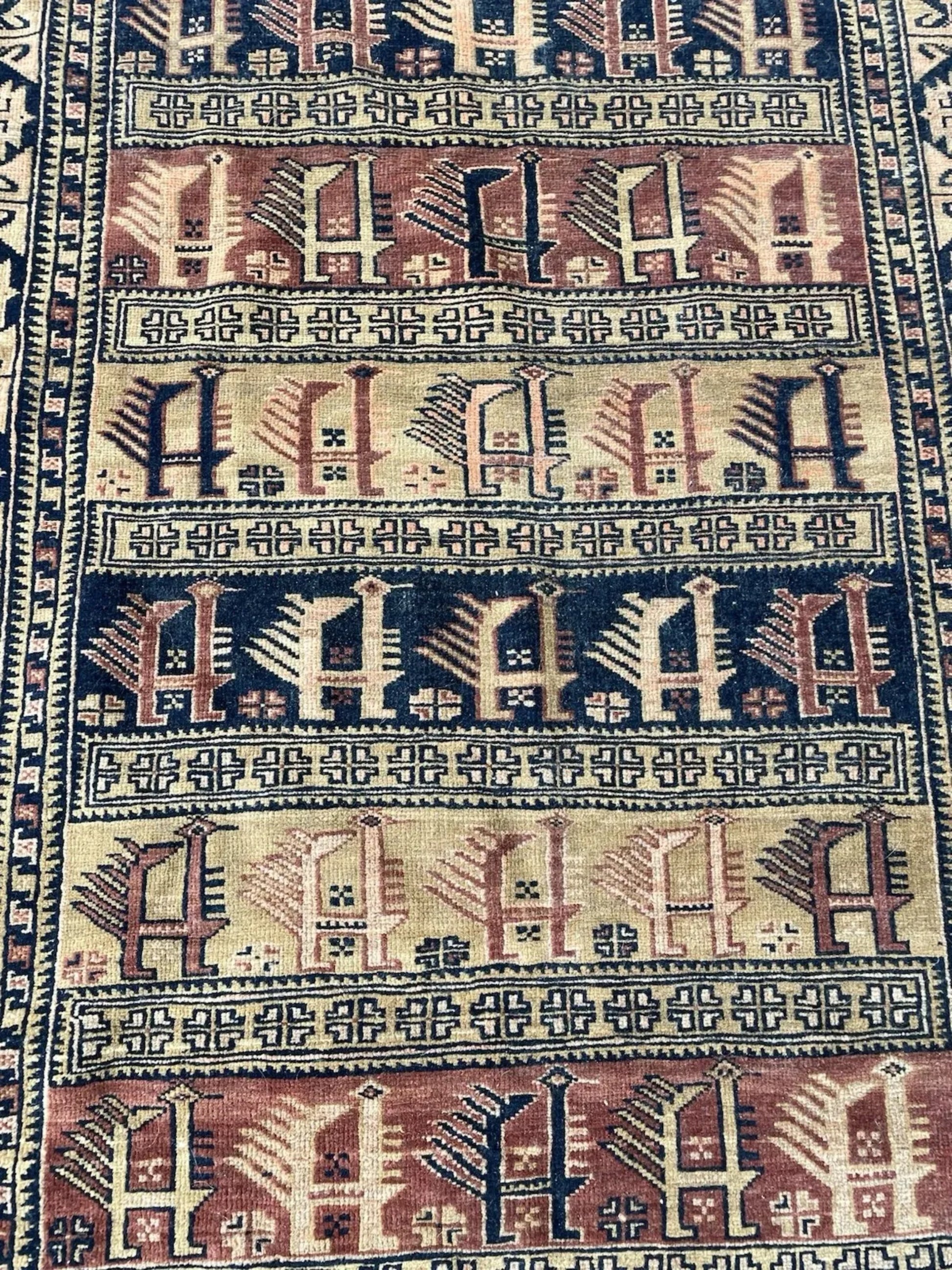 Full front view of the antique Baluch rug showing its all-over geometric design.

