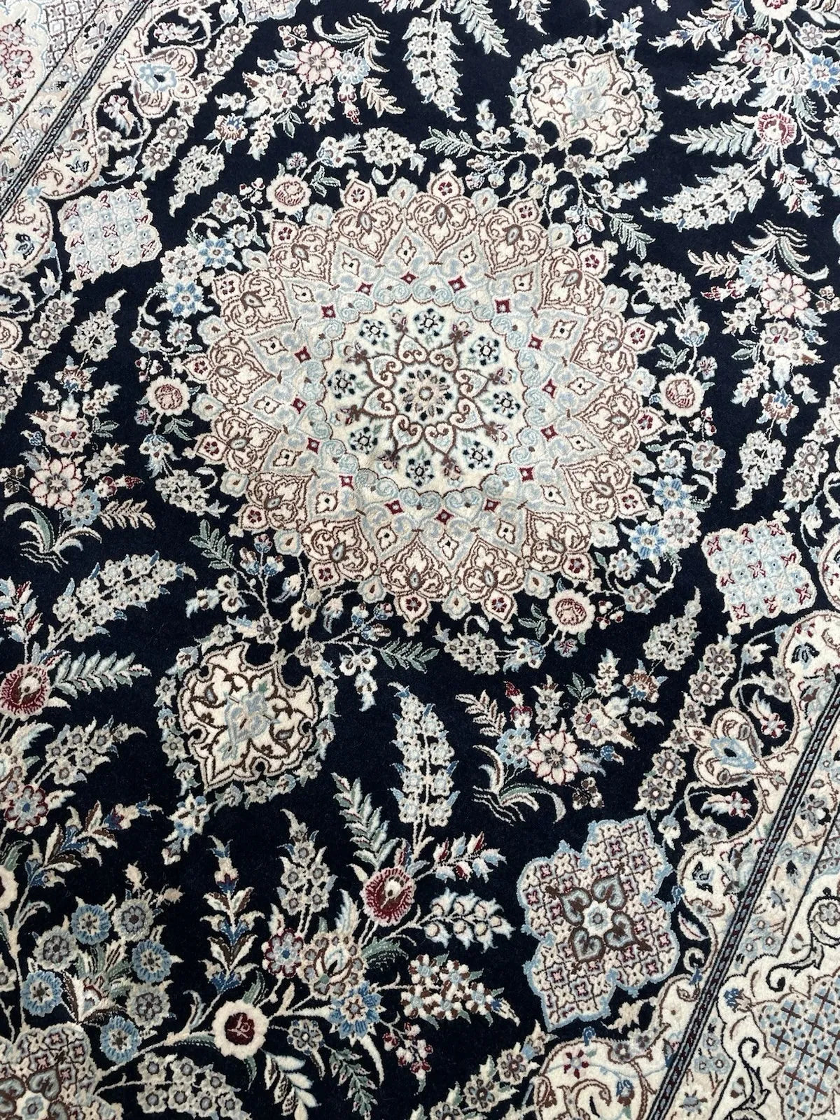 Vintage Persian rug showing intricate navy field with ivory floral arabesques and subtle burgundy accents.


