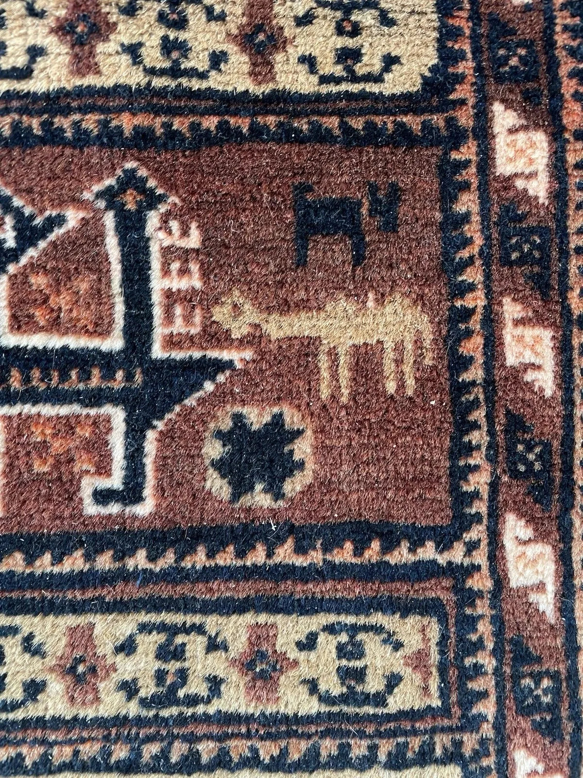 Traditional Baluch weaving pattern featuring a narrative composition of stacked bands, each containing unique tribal emblems.

