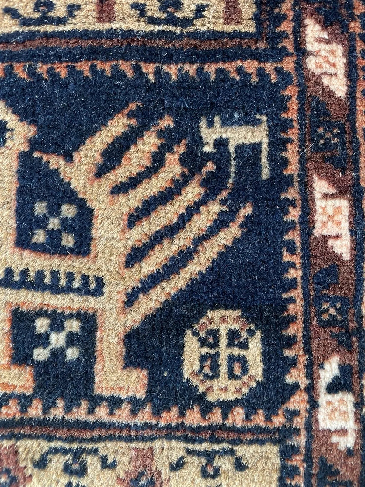 Earthy antique rug with deep brown field, camel-colored motifs, ivory accents, and touches of dark navy – all hand-spun wool.

