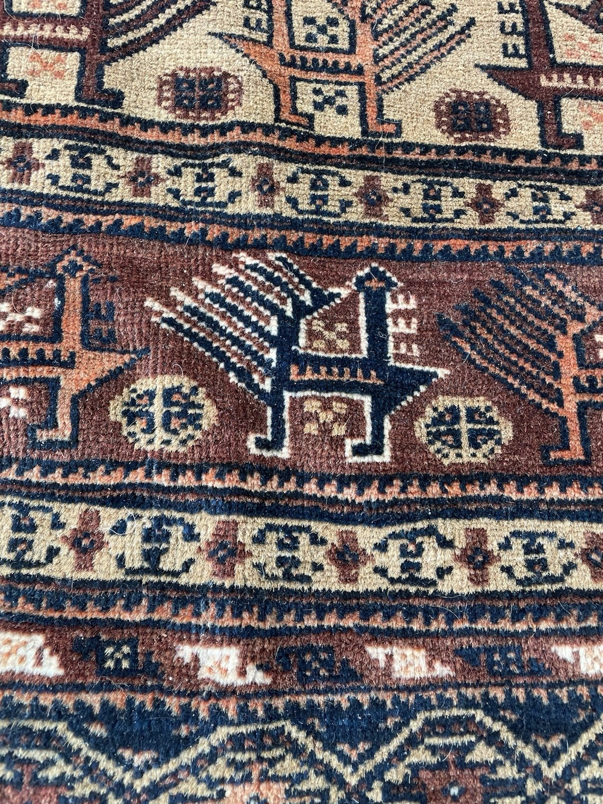 High-contrast tribal design using natural dyes: rich browns against ivory and camel, typical of early 20th-century Baluch weaving.

