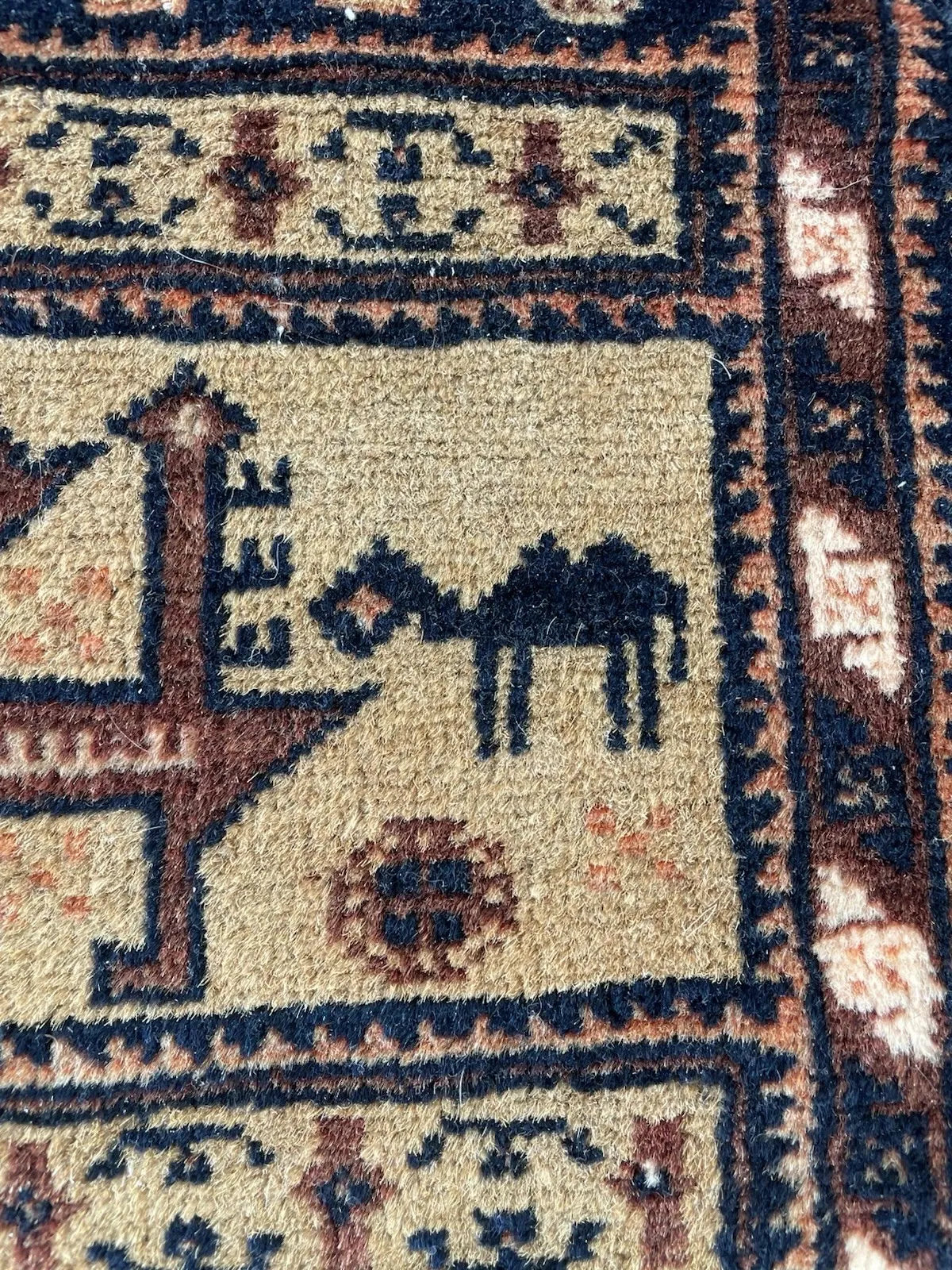 1920s Afghan Baluch tribal rug with geometric patterns, symbolic birds, and tree forms arranged in horizontal bands on a wool foundation.

