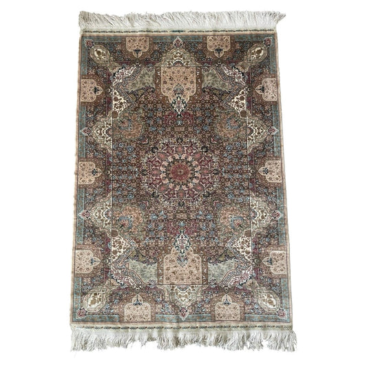 Close up view of a vintage Turkish Hereke silk rug from the 1970s featuring an intricate central medallion, floral motifs, and a soft ivory and rose color palette.

