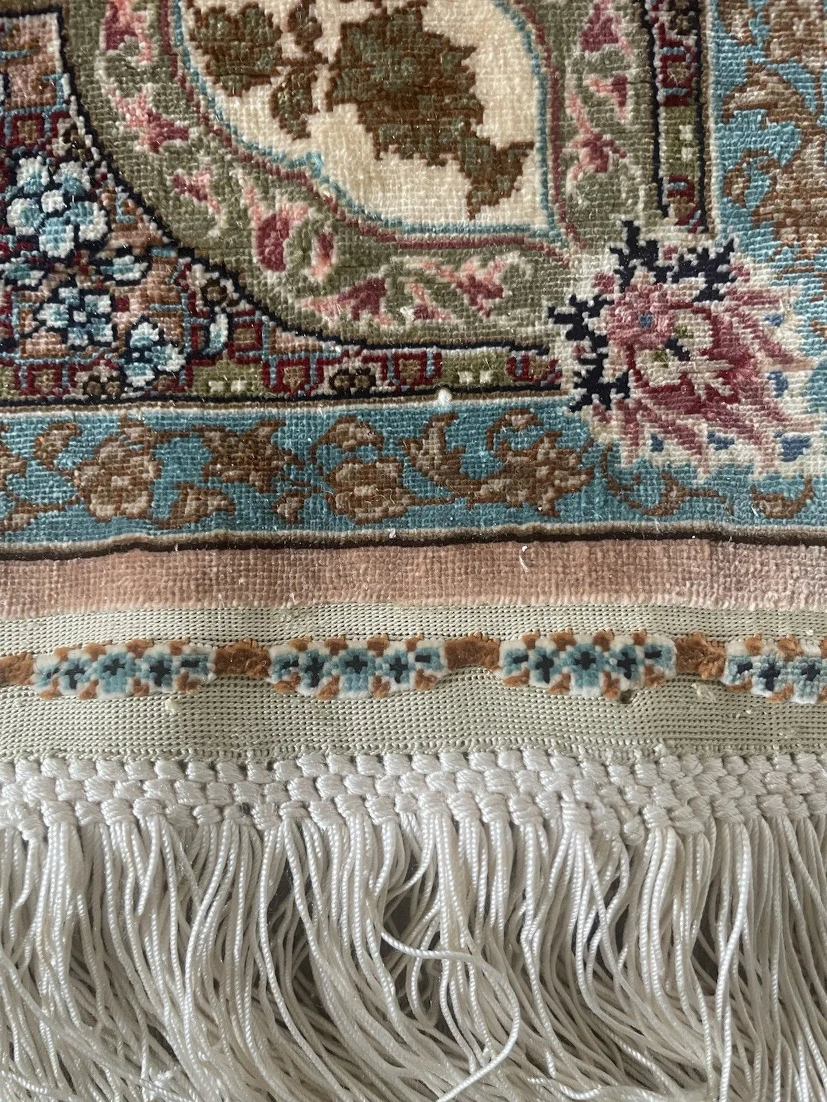 Soft luminous Turkish Hereke silk rug with a central radial medallion, aqua blue highlights, and warm earth tone borders.

