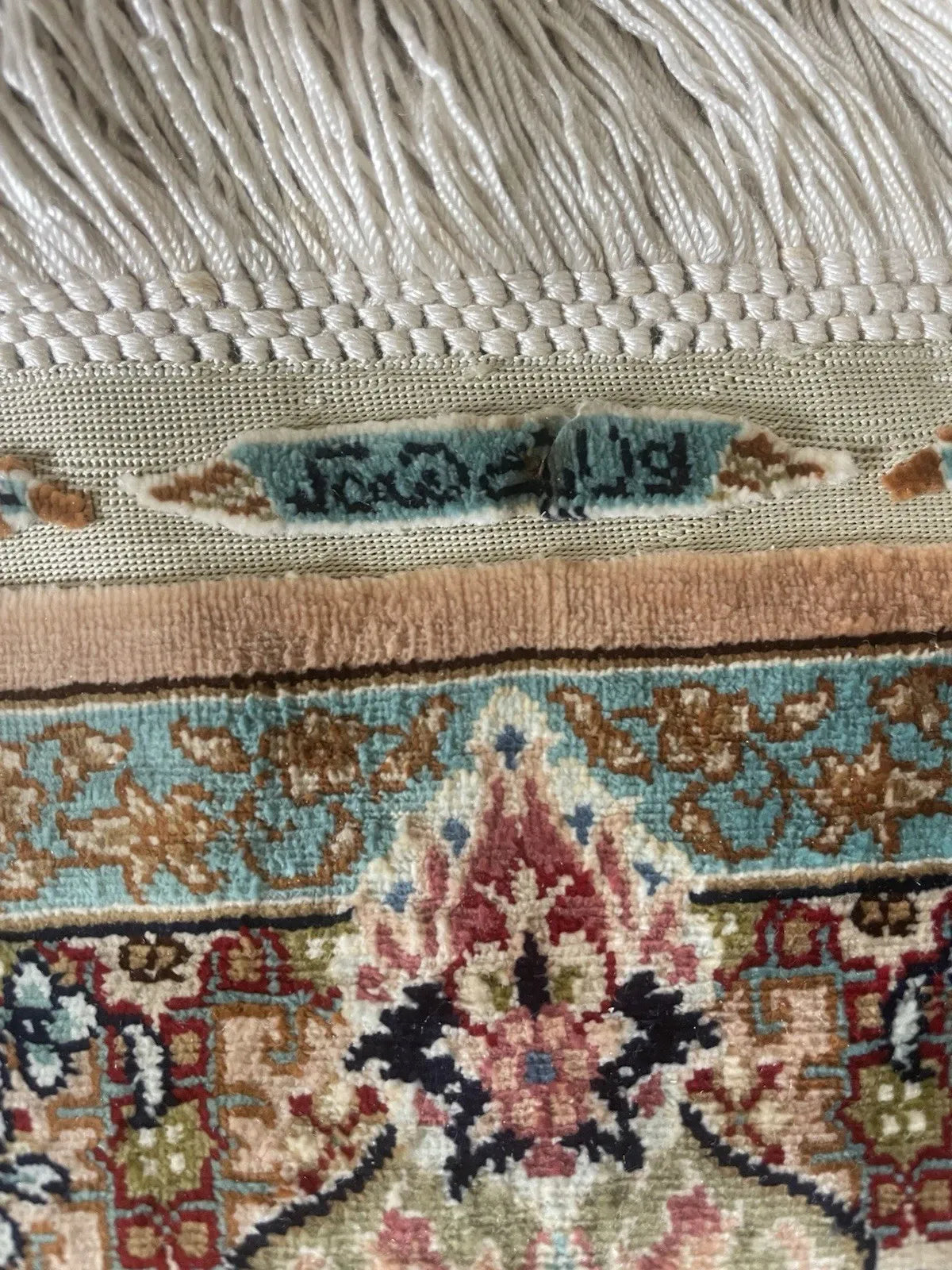 Collectible 1970s Turkish Hereke silk rug displayed as a wall hanging, highlighting its subtle pastel palette and even vintage wear.

