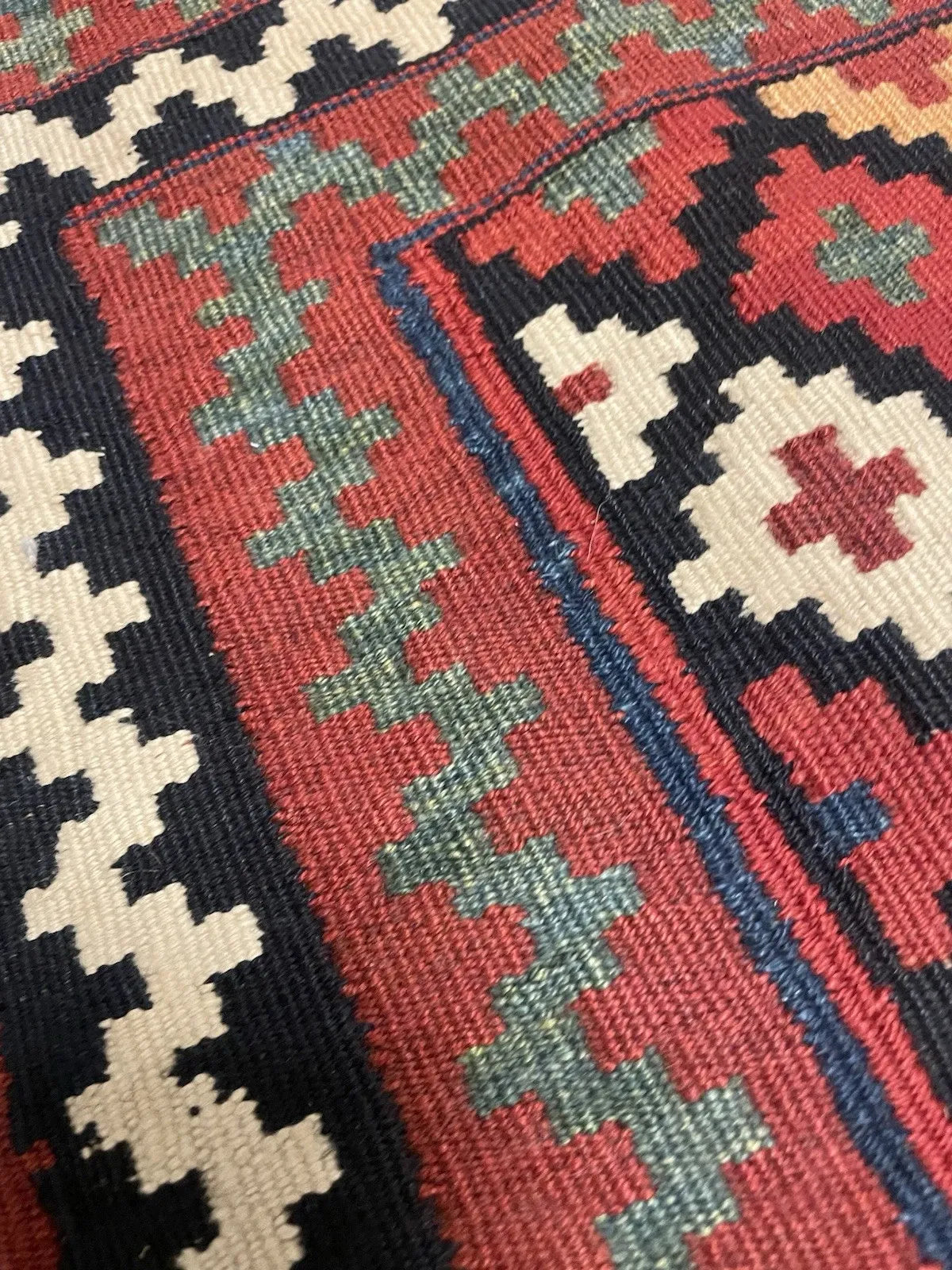 Close-up of the central field on a circa 1900 Qashqai bagface kilim, showing significant surface wear, fiber loss, and abraded weft threads consistent with 120+ years of nomadic use, with strong unfaded colors.

