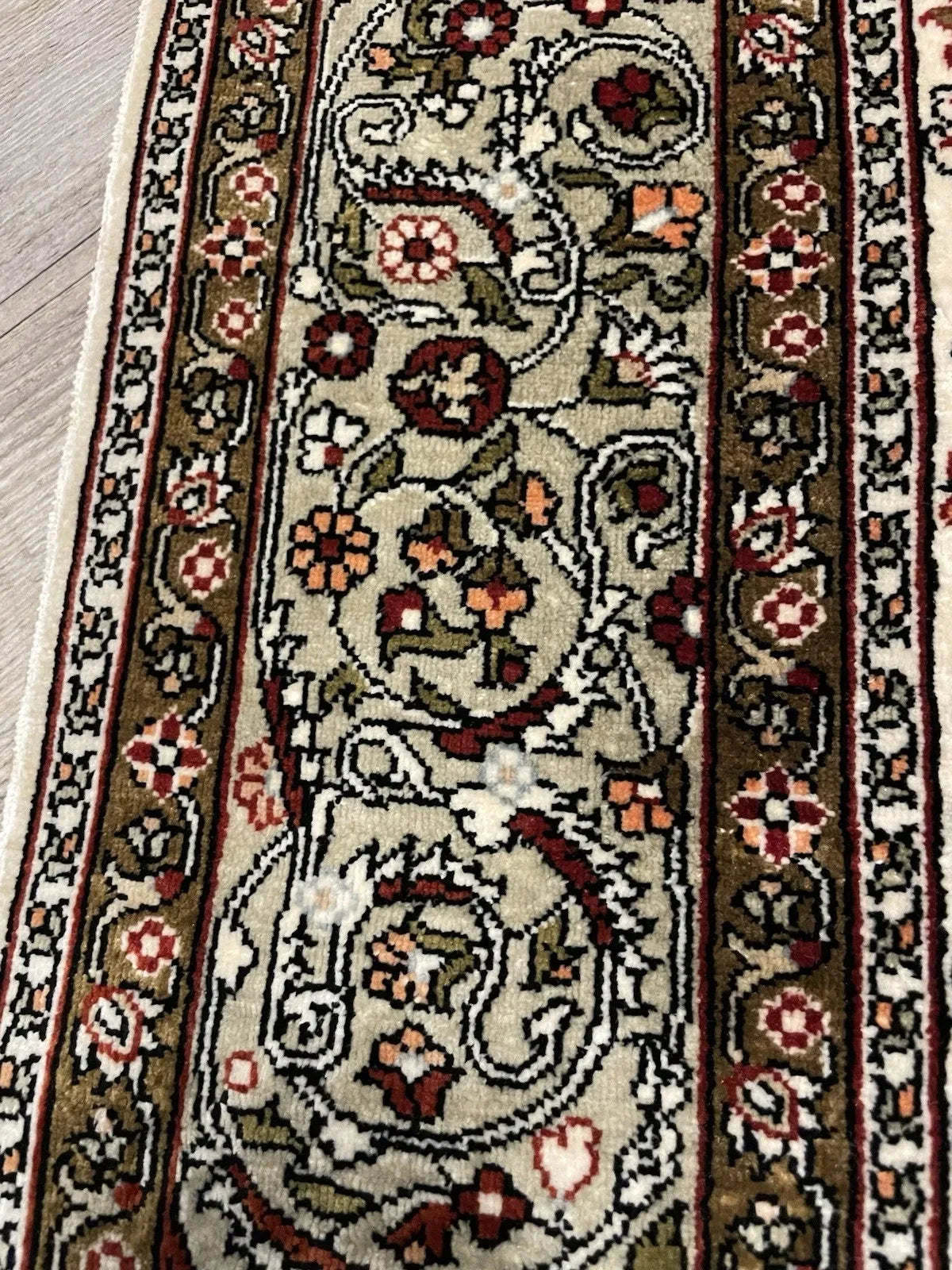 Detail of the mihrab arch apex on a Turkish Hereke silk rug, showing elegant dark Arabic calligraphy "Allahu Akbar" rendered with the precision of master calligraphy translated into silk.

