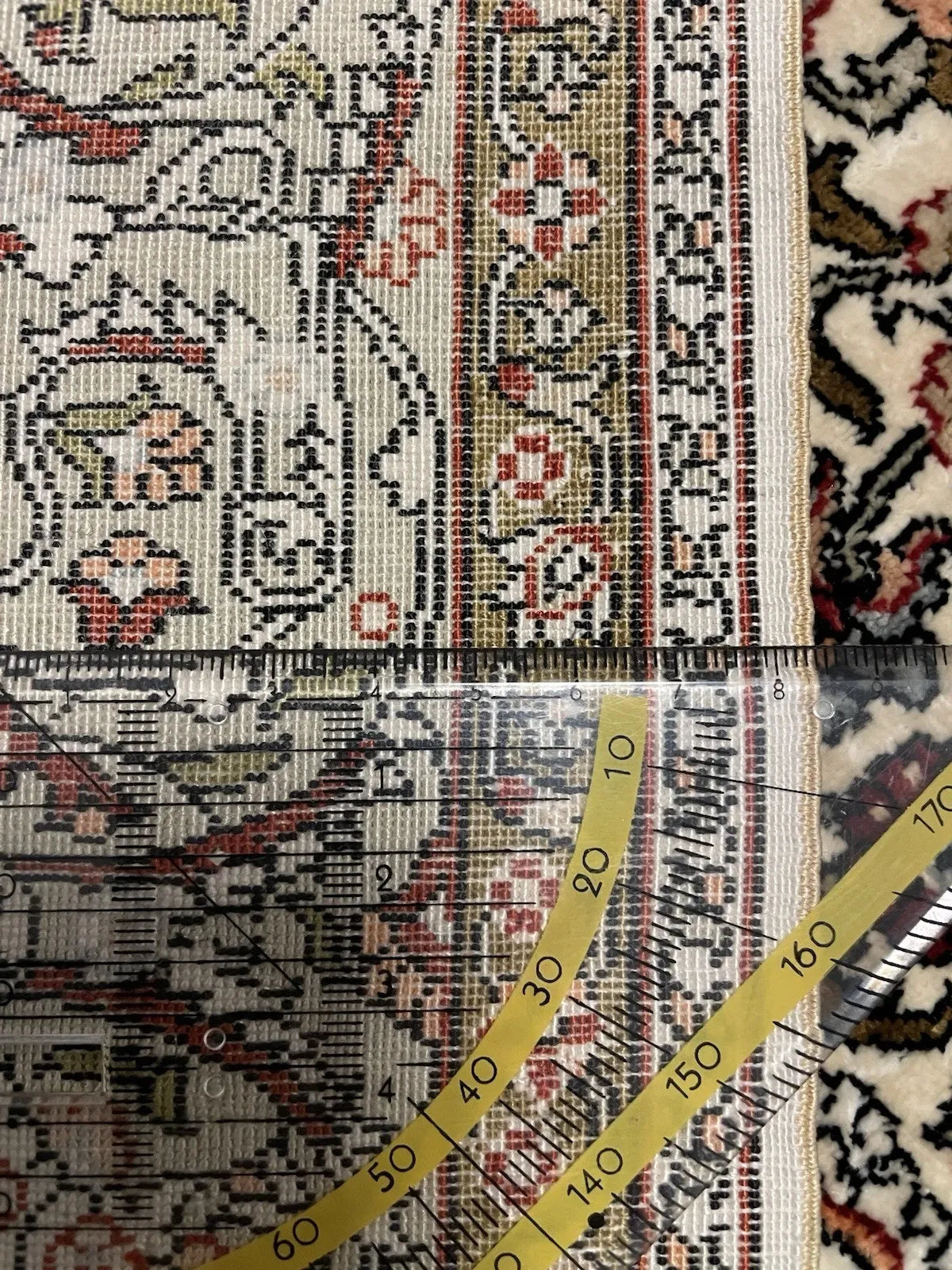 Close-up of the simurgh/phoenix motif on a vintage Hereke silk carpet, showing individual barb detail on wing feathers and a long curving tail of great elegance against an ivory silk ground.

