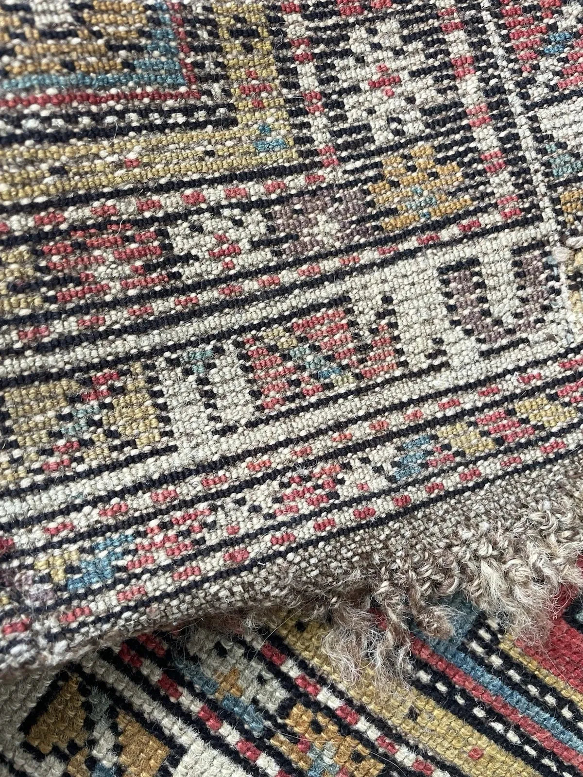 Antique Caucasian rug measuring 4' × 3'2", hand-knotted with Turkish symmetrical knots, wool pile on wool foundation, in distressed condition with low pile and significant end wear.

