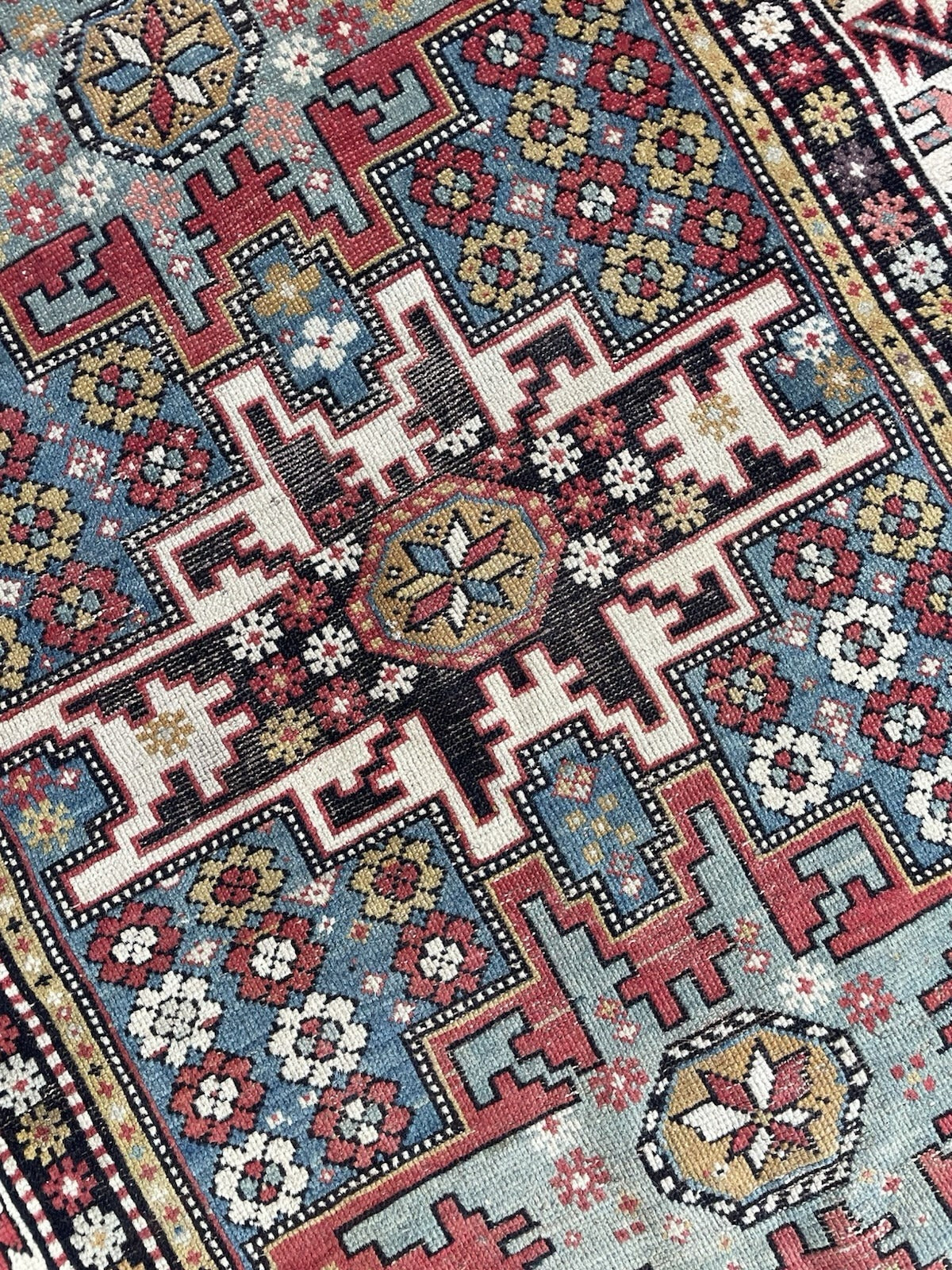 Full view of a distressed antique Shirvan rug ideal for wall display, with strong unfaded natural dye colors (indigo blue, madder crimson, camel gold) and fully legible pattern despite low pile and end wear.

