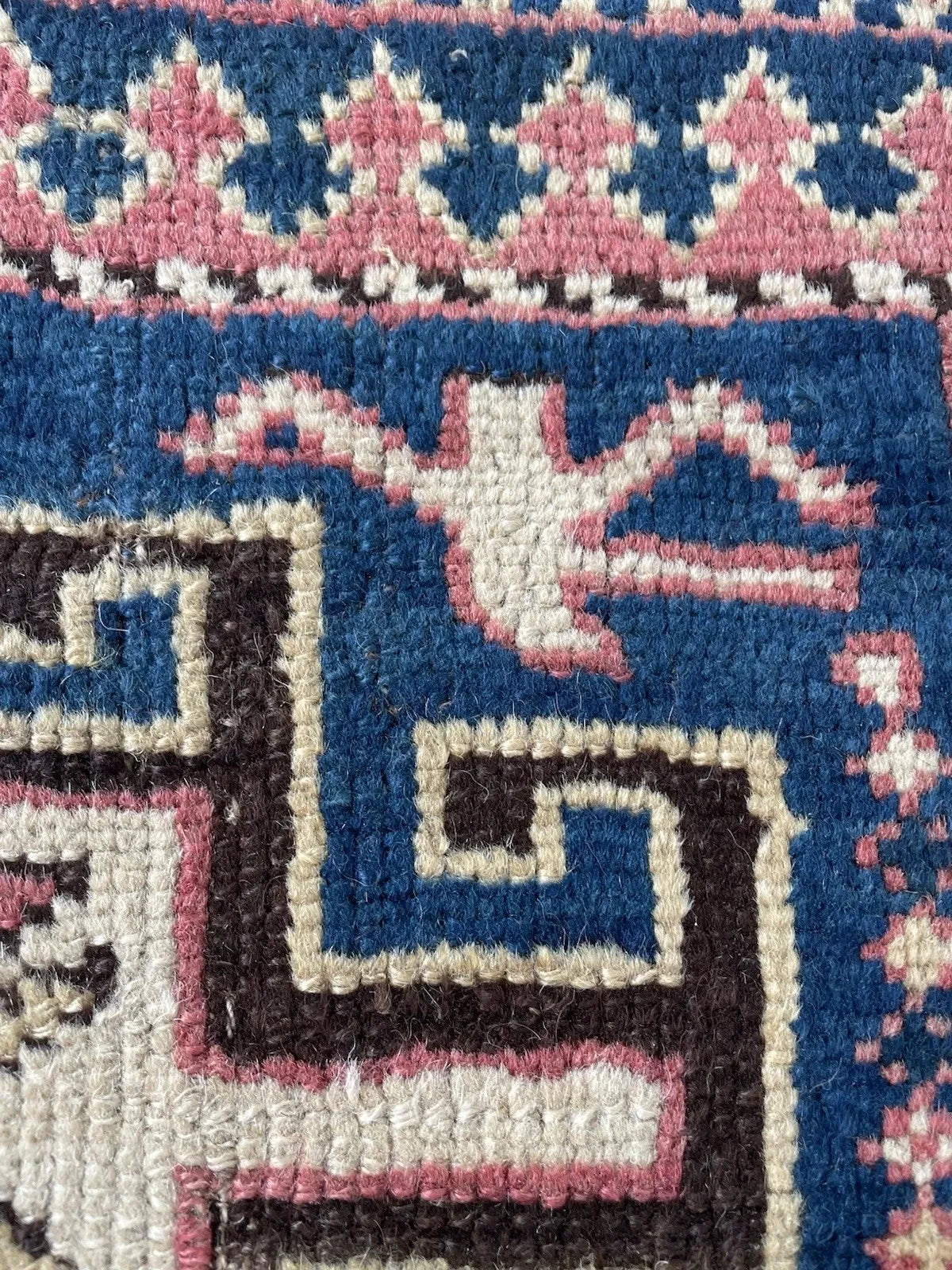 Full view of a circa 1880 Kazak tribal rug with a royal blue indigo field filled with geometric filler motifs including hooked diamonds, small stars, reciprocal arrow forms, and stylized bird and animal silhouettes.

