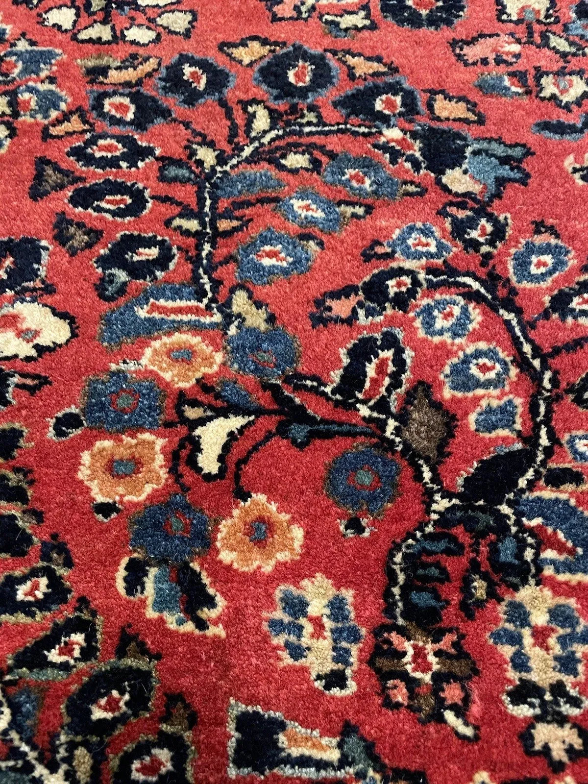 Antique handmade rug in Sarouk style featuring a central geometric floristry medallion, sinuous arabesques, and narrow guard borders of reciprocal vine and rosette.

