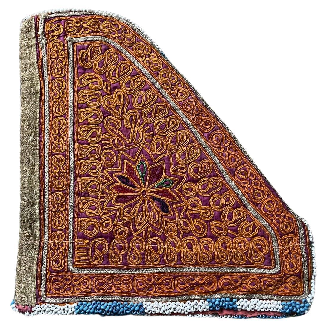 Close-up view of a handmade antique Uzbek Suzani collectible bag (1920s) featuring vibrant floral and geometric embroidery in red, gold, and purple.