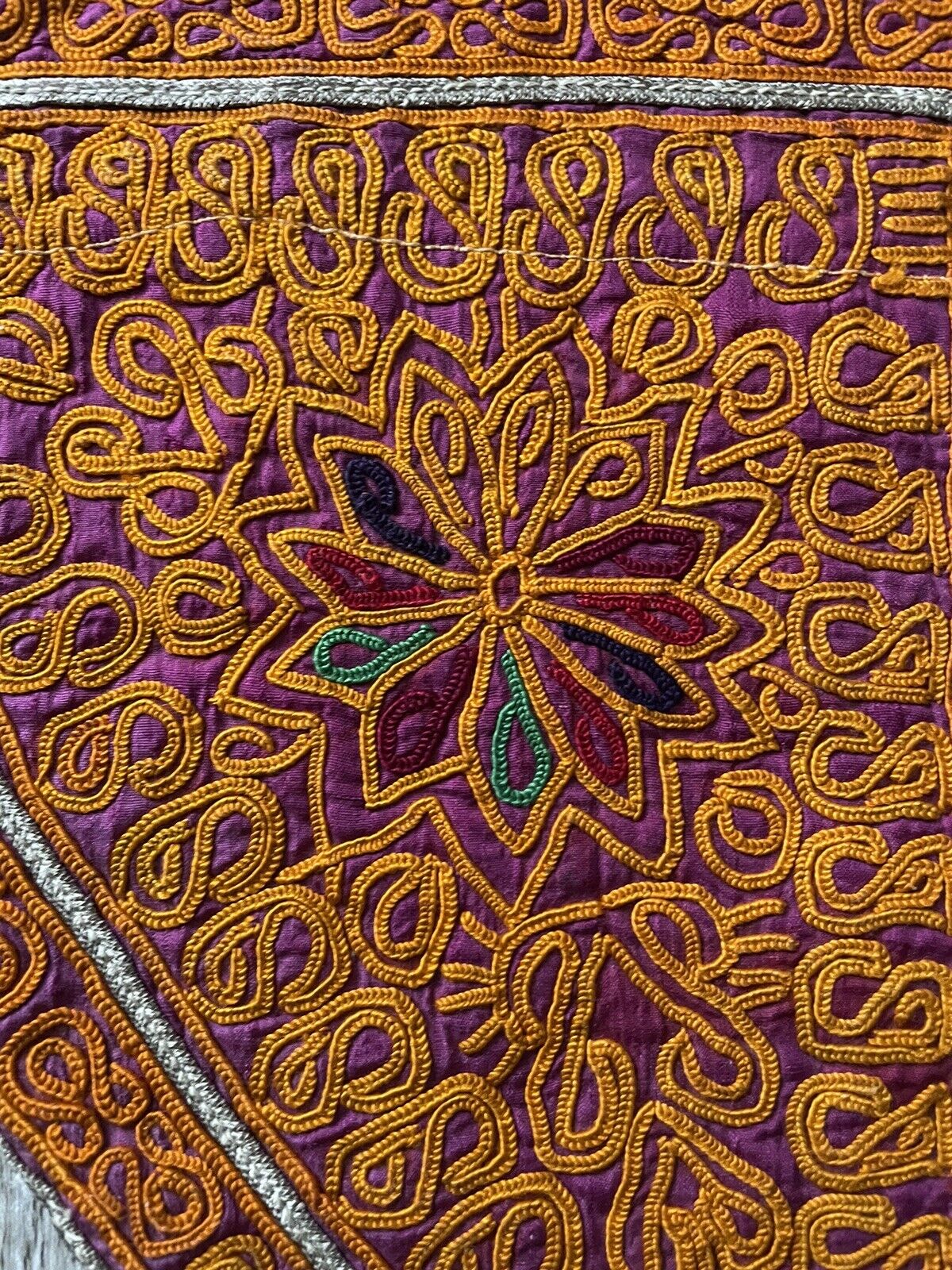 Close-up of the intricate red floral embroidery on a handmade antique Uzbek Suzani collectible bag