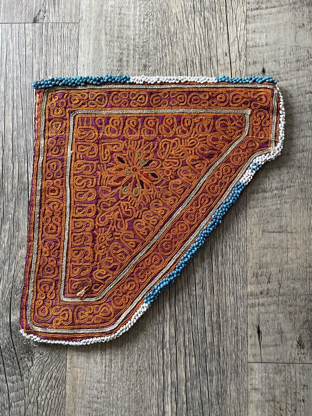 Close-up of the detailed gold geometric patterns on a handmade antique Uzbek Suzani collectible bag (1920s).