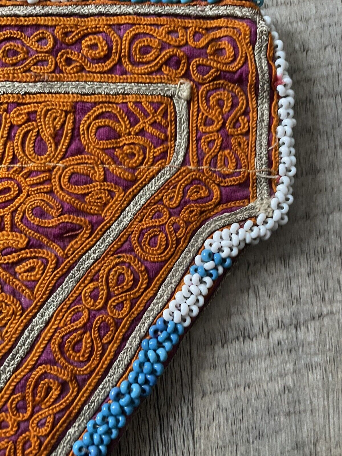The handmade antique Uzbek Suzani collectible bag (1920s) displayed on a shelf with other collectible items.