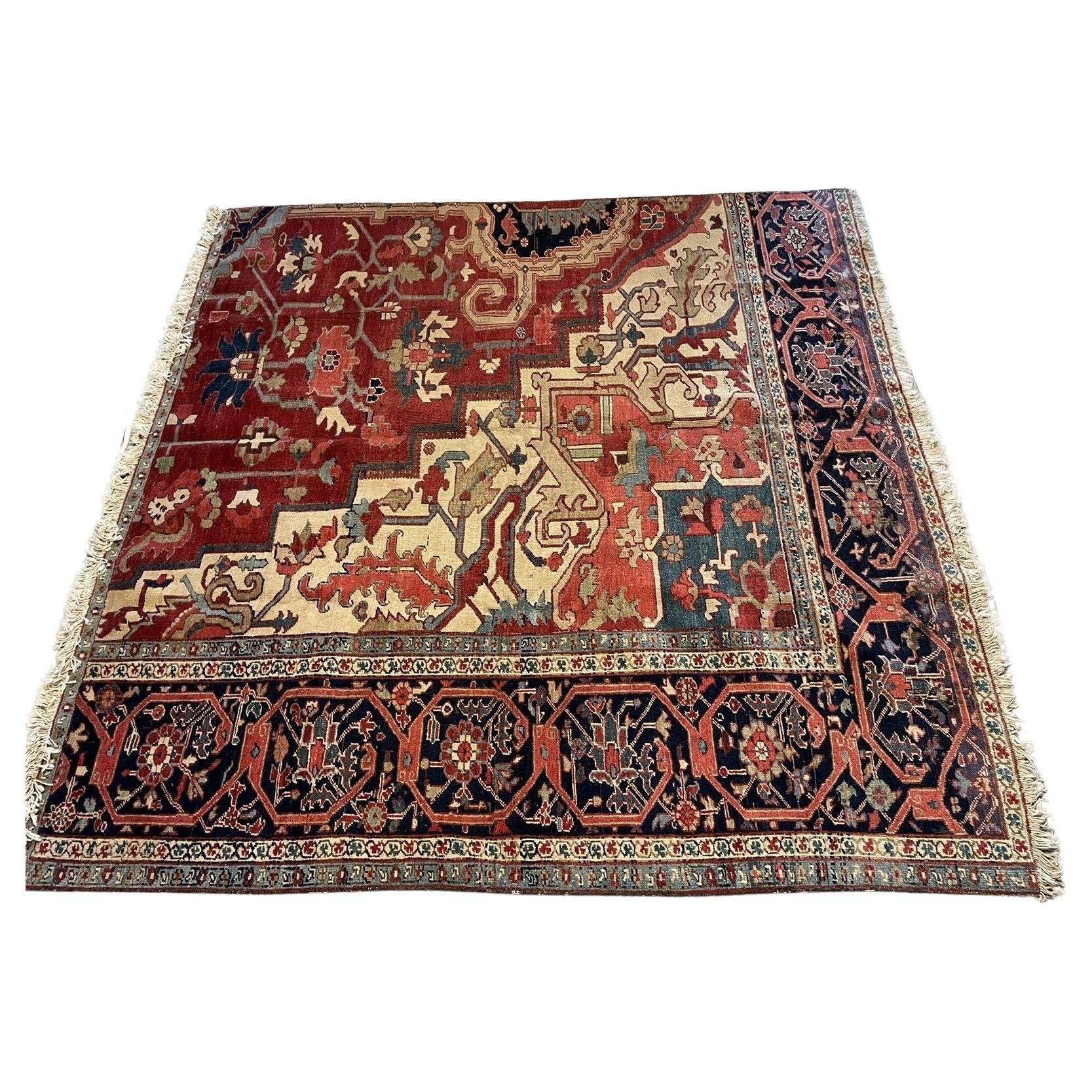 A close-up view of a captivating section of a handmade antique Persian Heriz Vagireh rug (1880s), showcasing a central medallion design in rich red tones with intricate black and ivory floral motifs. The surrounding geometric borders display a harmonious blend of red, black, and other colors.