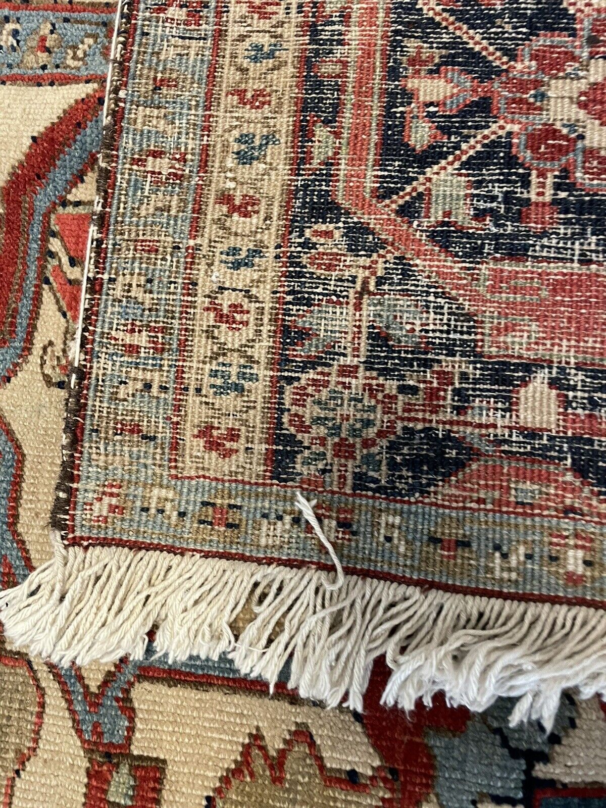The underside of a handmade antique Persian Heriz Vagireh rug (1880s), revealing the intricate web of wool yarns in a warm, natural color. The visible knots demonstrate the meticulous handwoven construction.