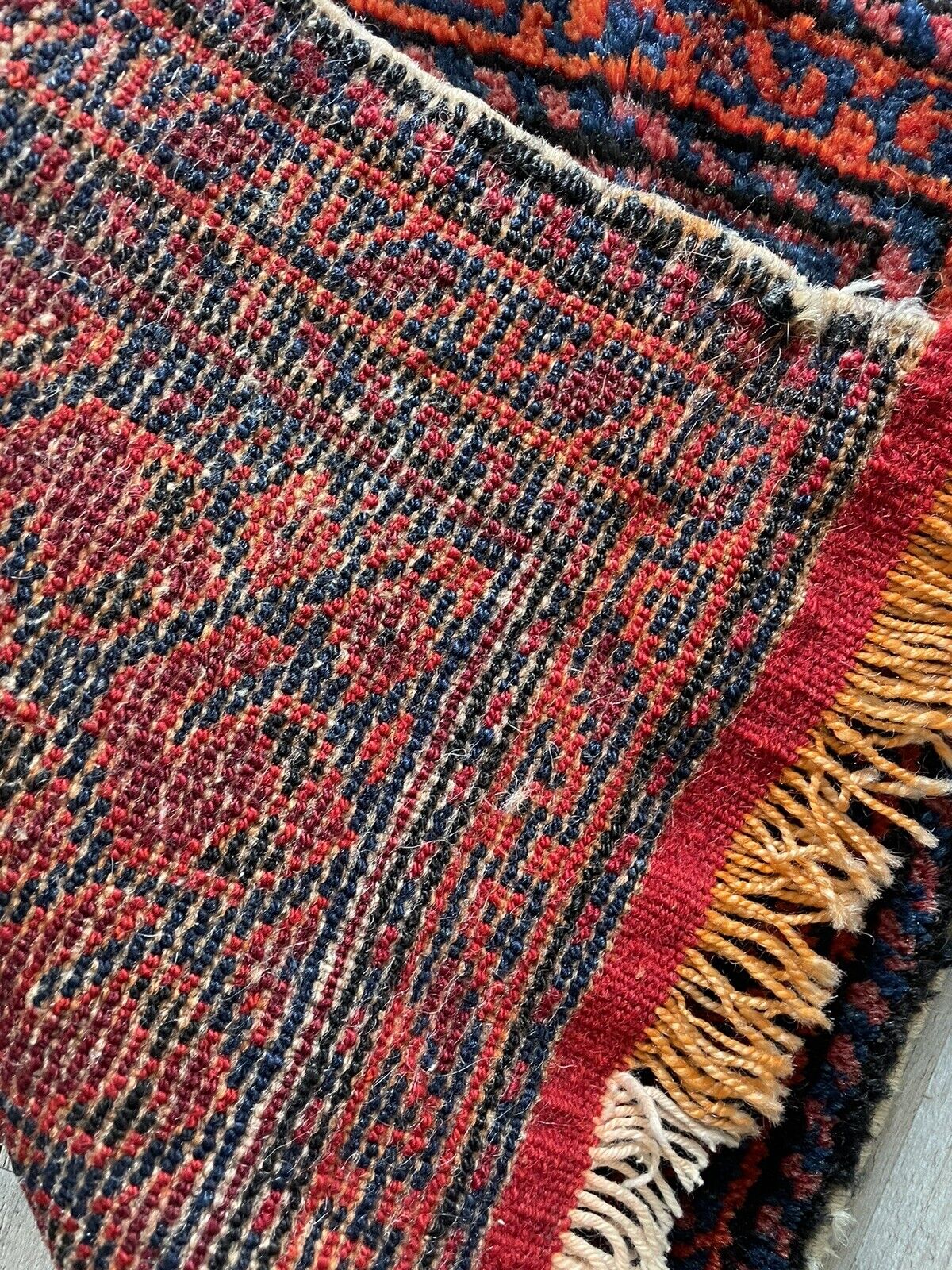 The backside of a handwoven antique Persian Shiraz bagface (1900s), revealing the natural wool fibers and the hand-knotted construction techniques used in its creation.