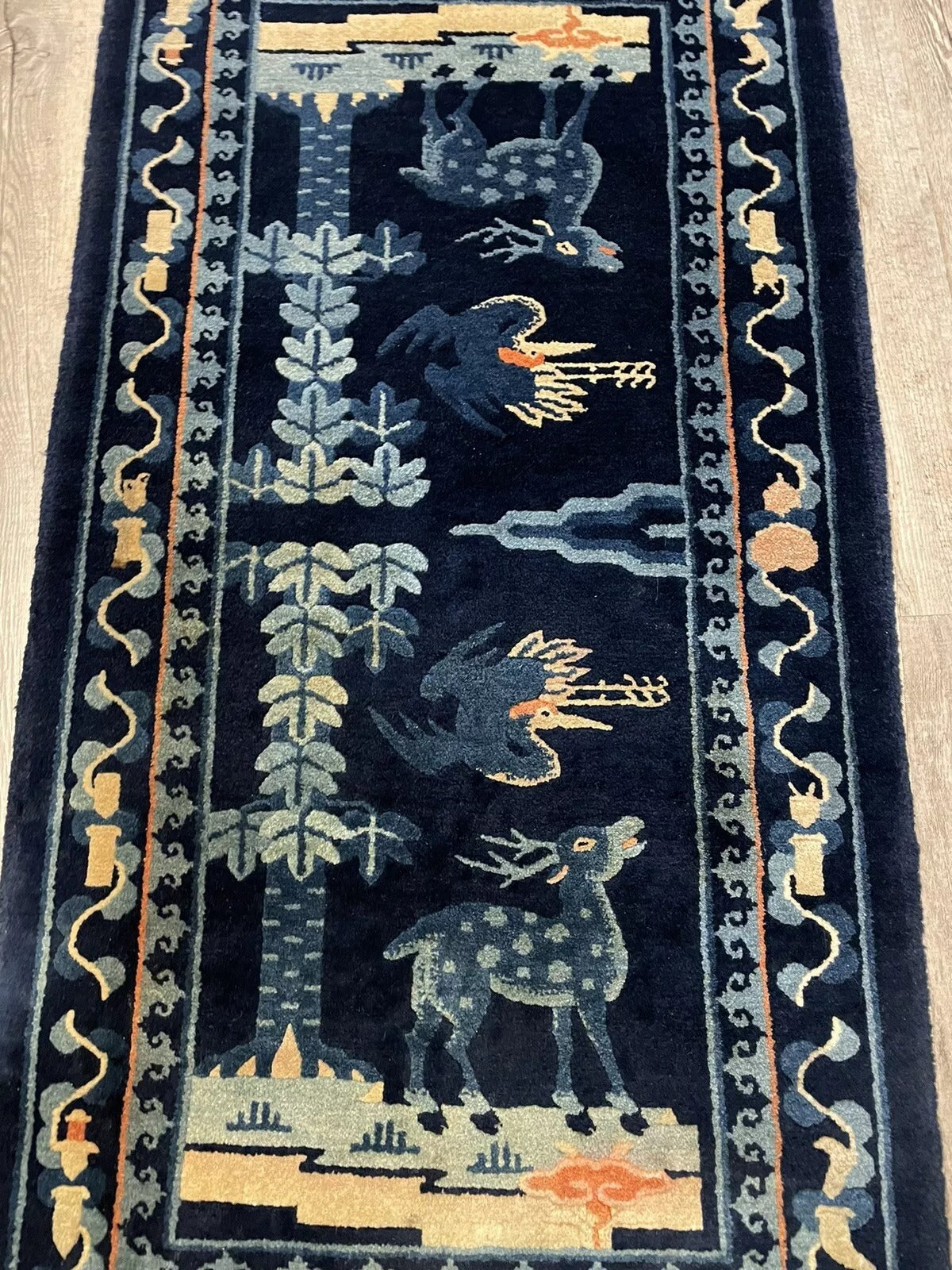 Deep blue background with deer and birds in an antique wool rug
