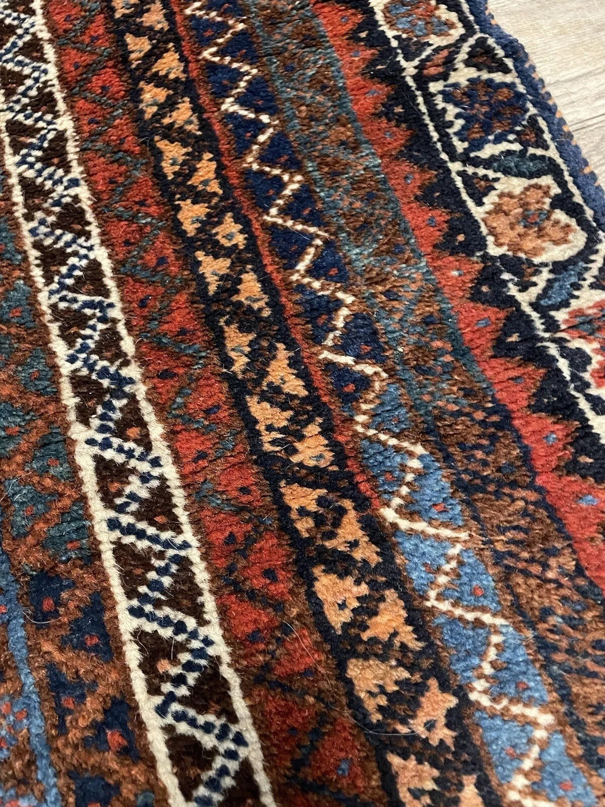 Red, blue, and brown geometric motifs on a Shiraz Persian rug
