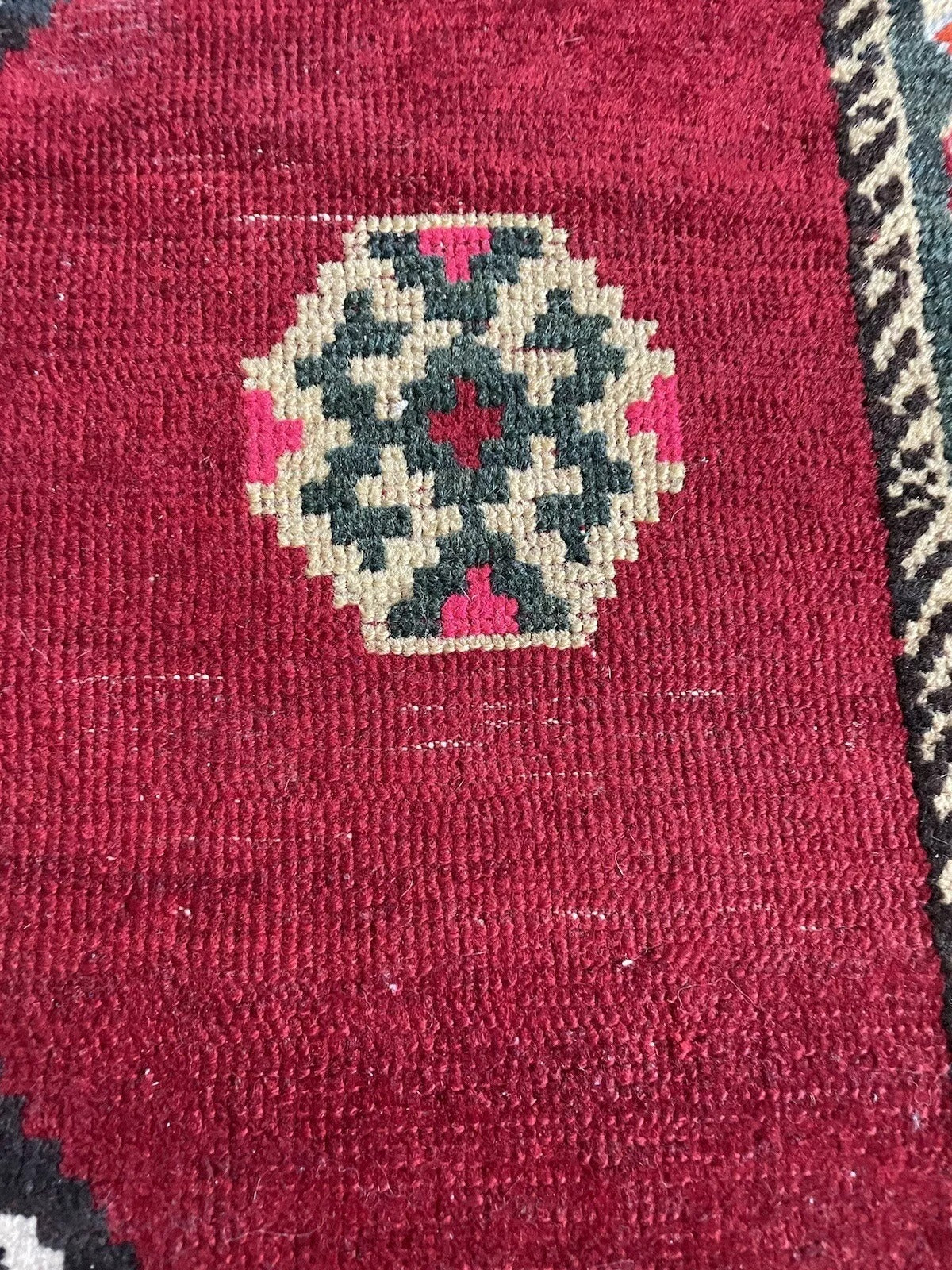 Vintage Persian Gabbeh rug featuring a deep red background and geometric accents
