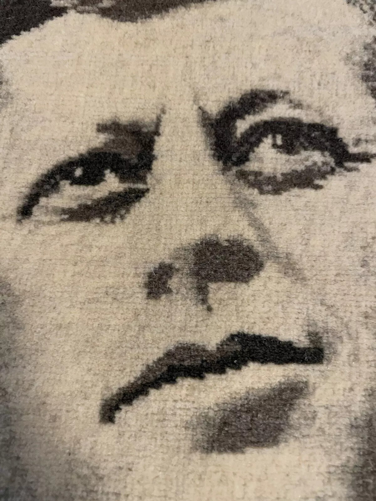 Black-and-white woven portrait of John F. Kennedy on a wool rug
