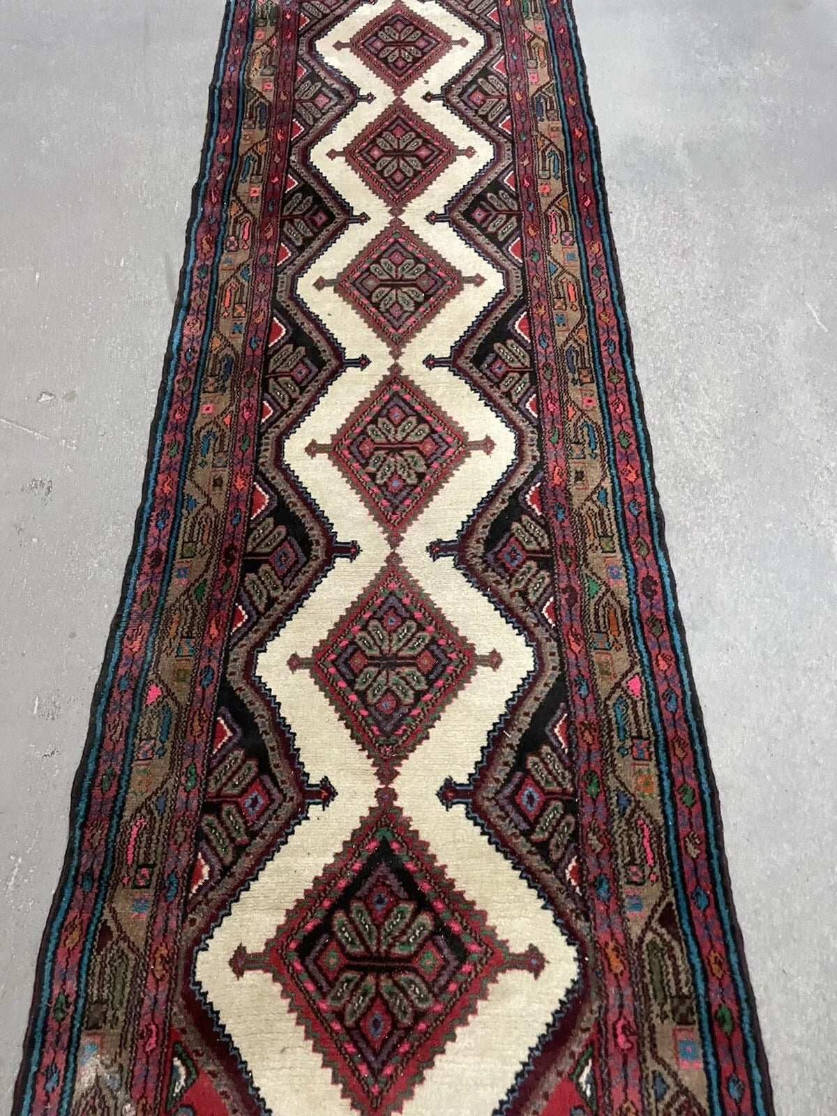Close-up of intricate border motifs on a vintage Hamadan runner
