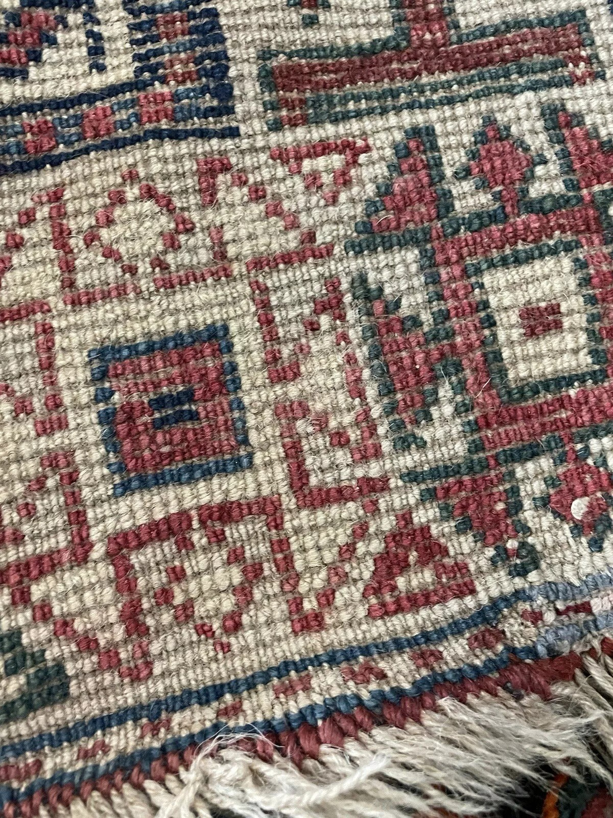 Close-up of intricate wool weaving on a 1900s Genje rug.

