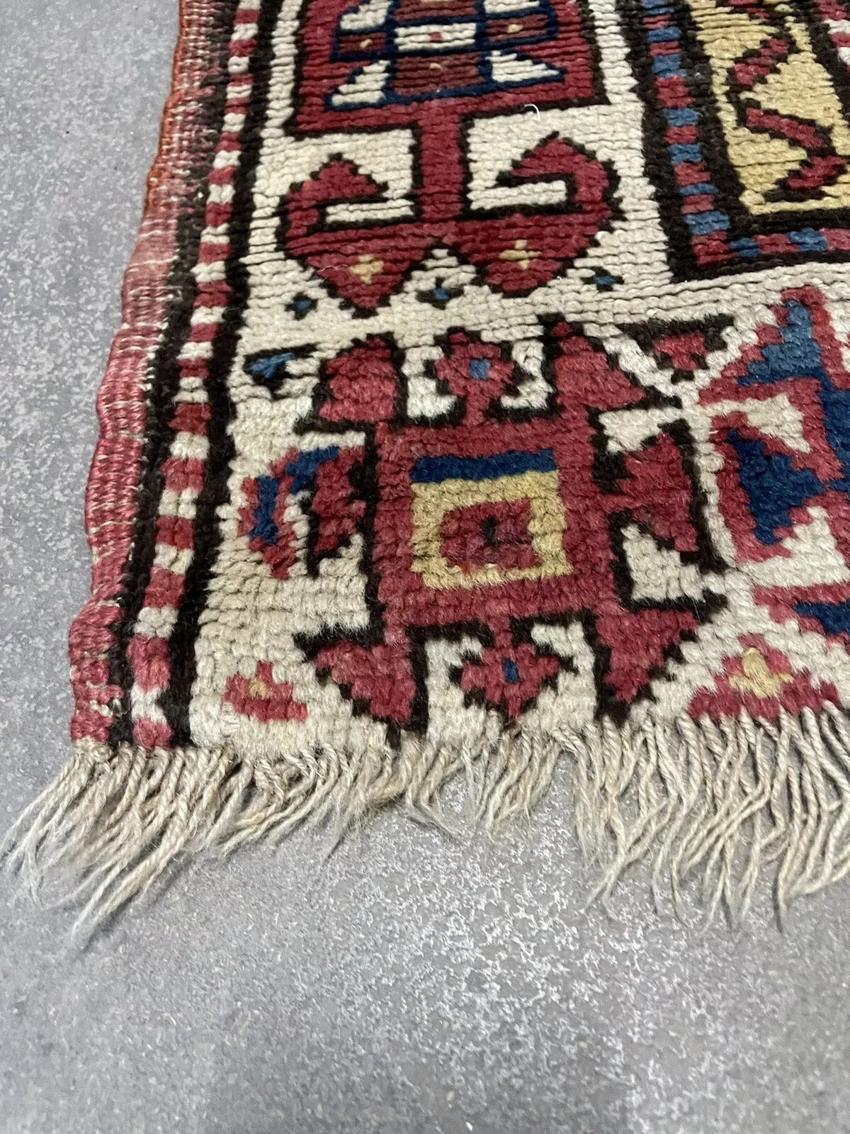 Close-up of the faded yet vibrant tones of an antique wool rug.

