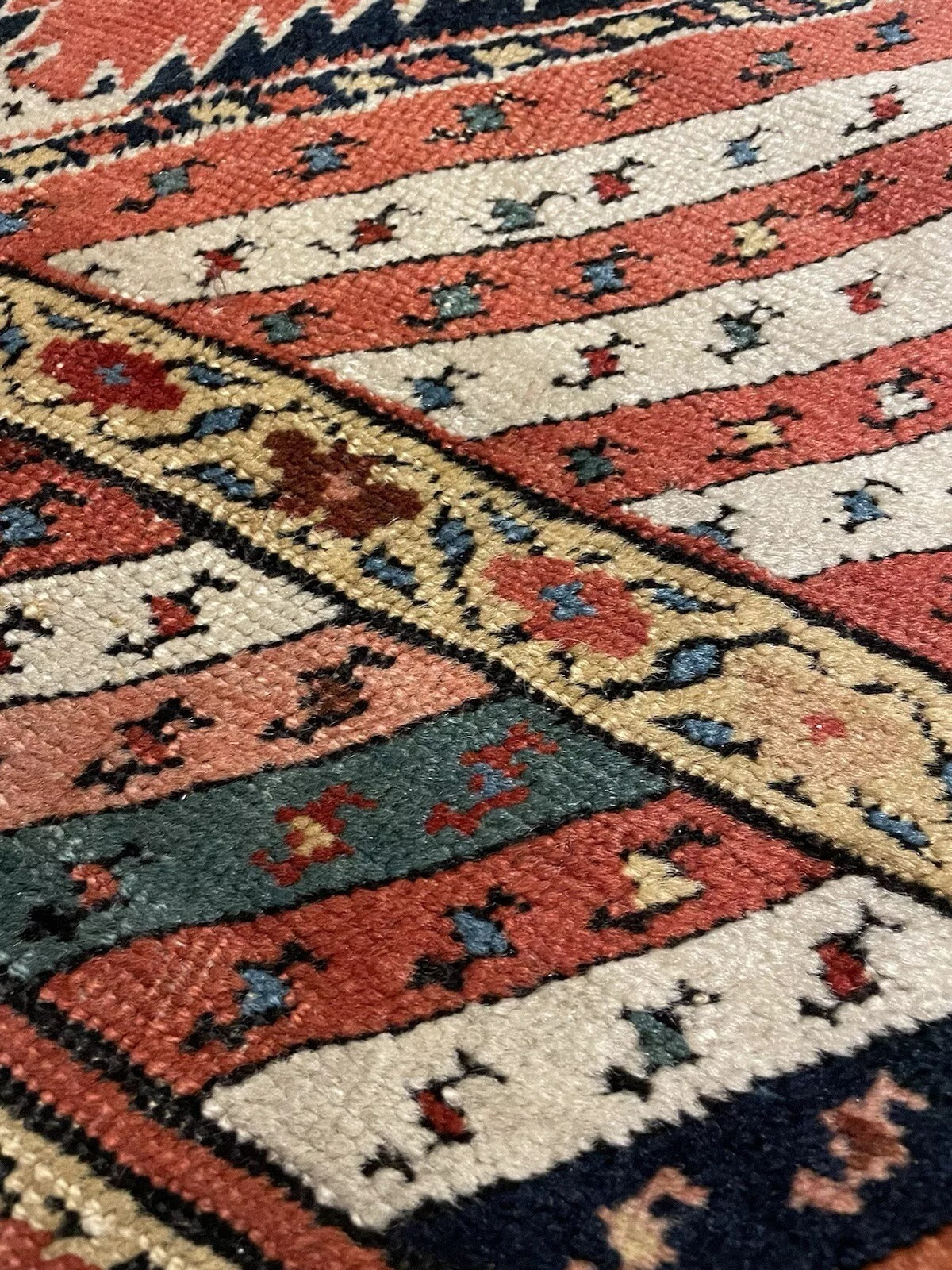 Woven pattern of Kurdish rug with deep terracotta background

