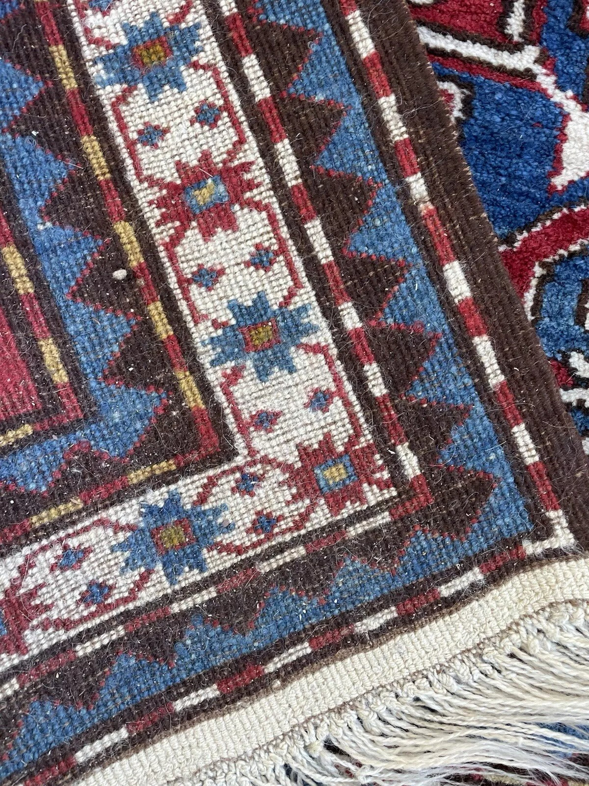 Detail of the intricate geometric border in shades of blue, red, and ivory.

