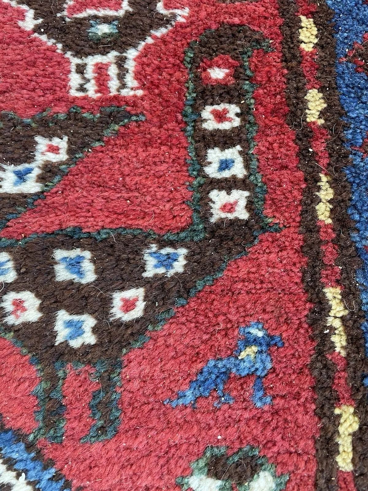 View of the entire rug highlighting the striking contrast between the red field and dark blue motifs.

