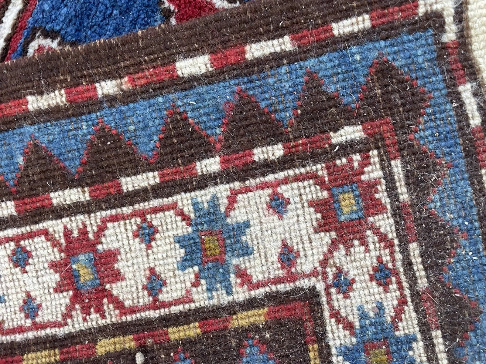 Detail of the rug's fringe and selvedge, showcasing its original antique condition.

