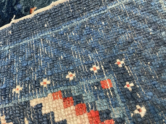 Close-up detail of the spotted deer and bird within the rug's decorative panel.