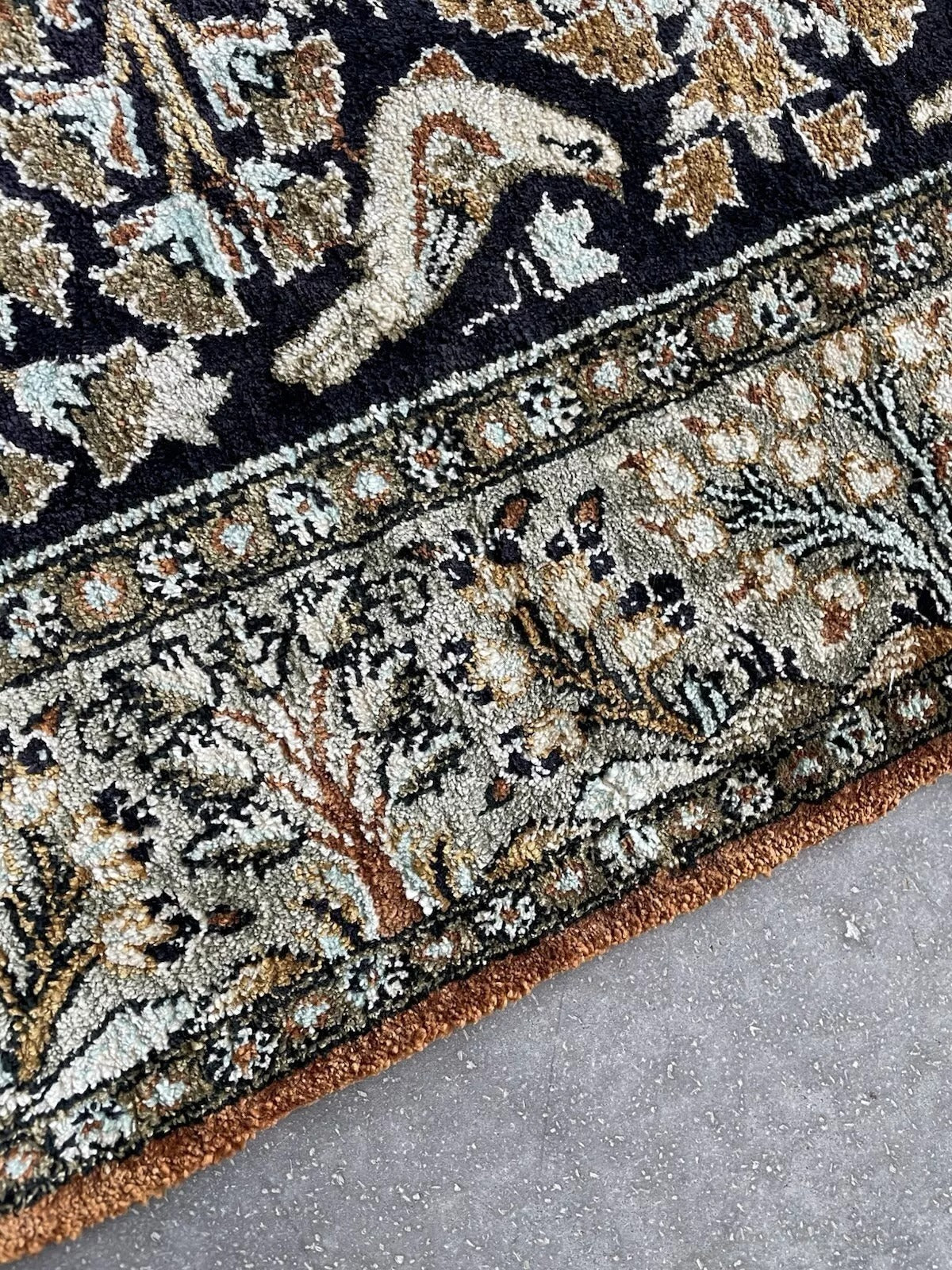 Close-up of a beautifully woven bird perched on a floral element.

