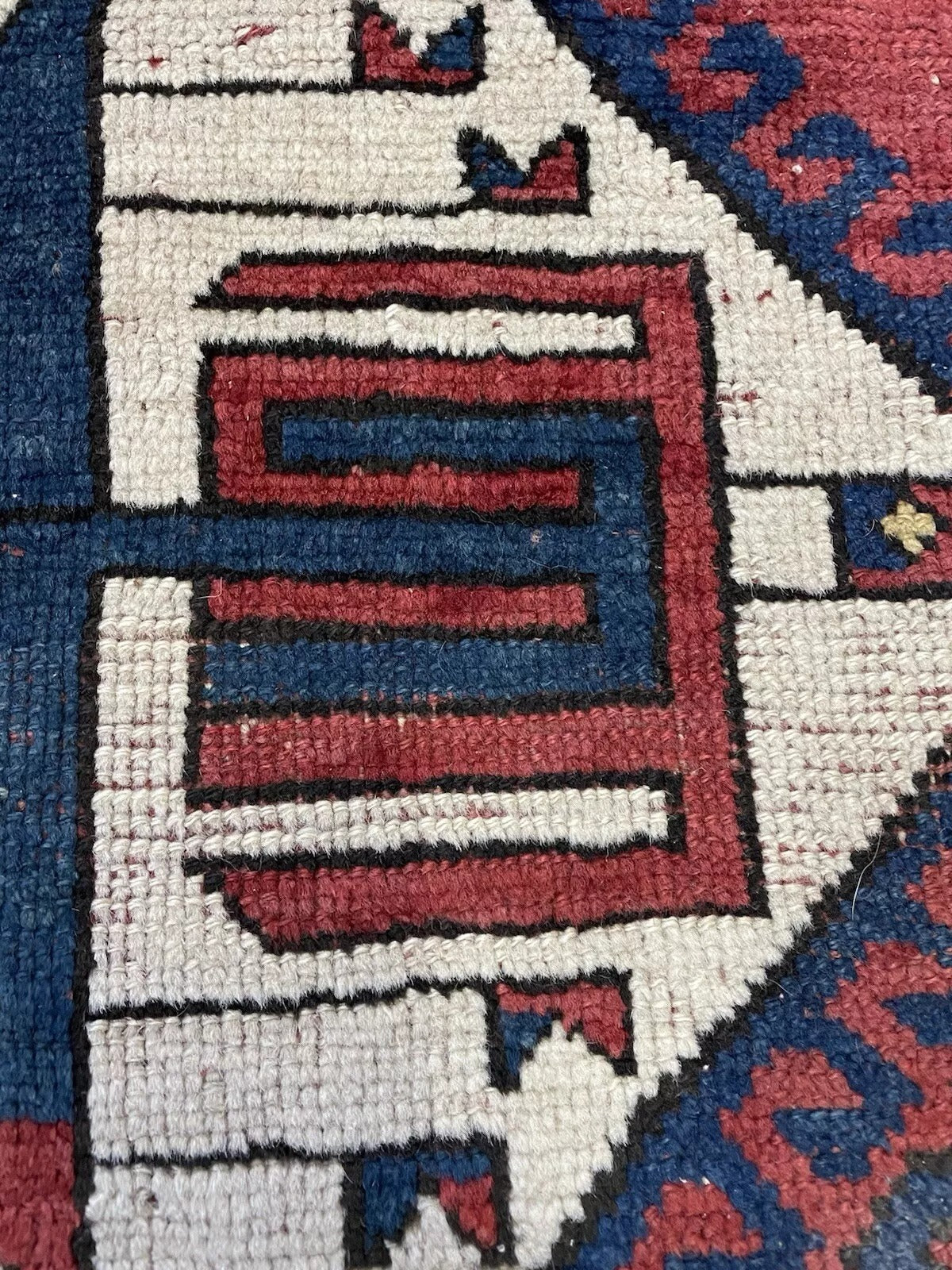 Texture shot showing the dense, hand-spun wool pile of the nomadic carpet.

