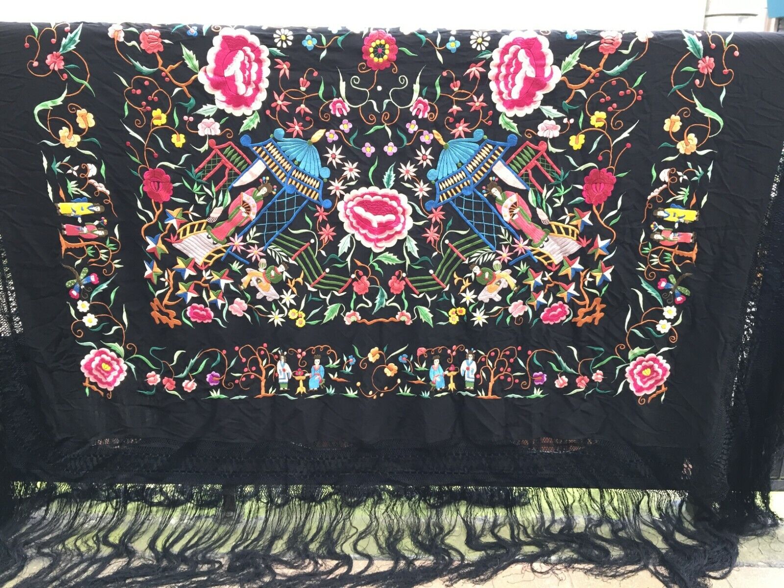 Close-up of the intricate silk embroideries depicting delicate flowers in shades of pink, white, and other colors against the black canvas