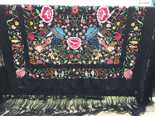 Close-up of the intricate silk embroideries depicting delicate flowers in shades of pink, white, and other colors against the black canvas