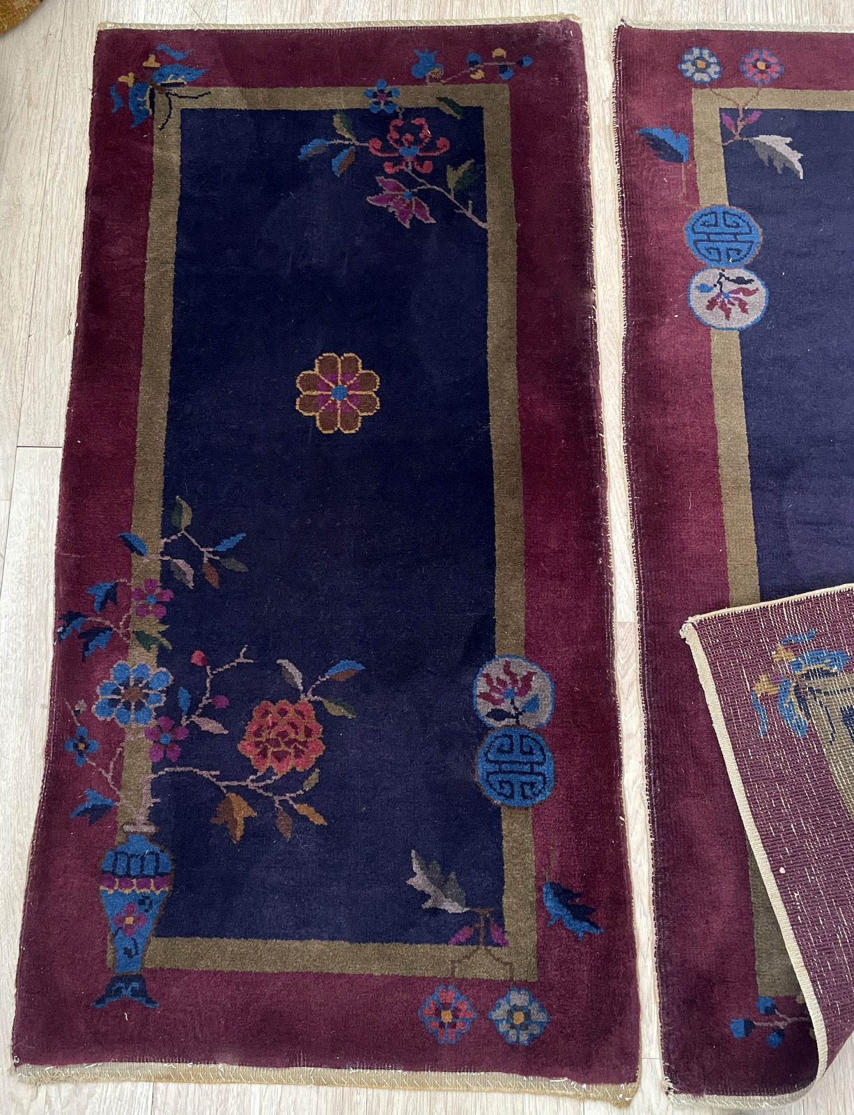 Stylized floral motif in coral and gold on the deep blue rug background.


