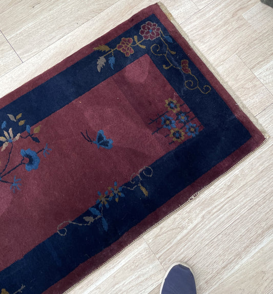 Close-up of the stylized blue floral motifs on maroon background.

