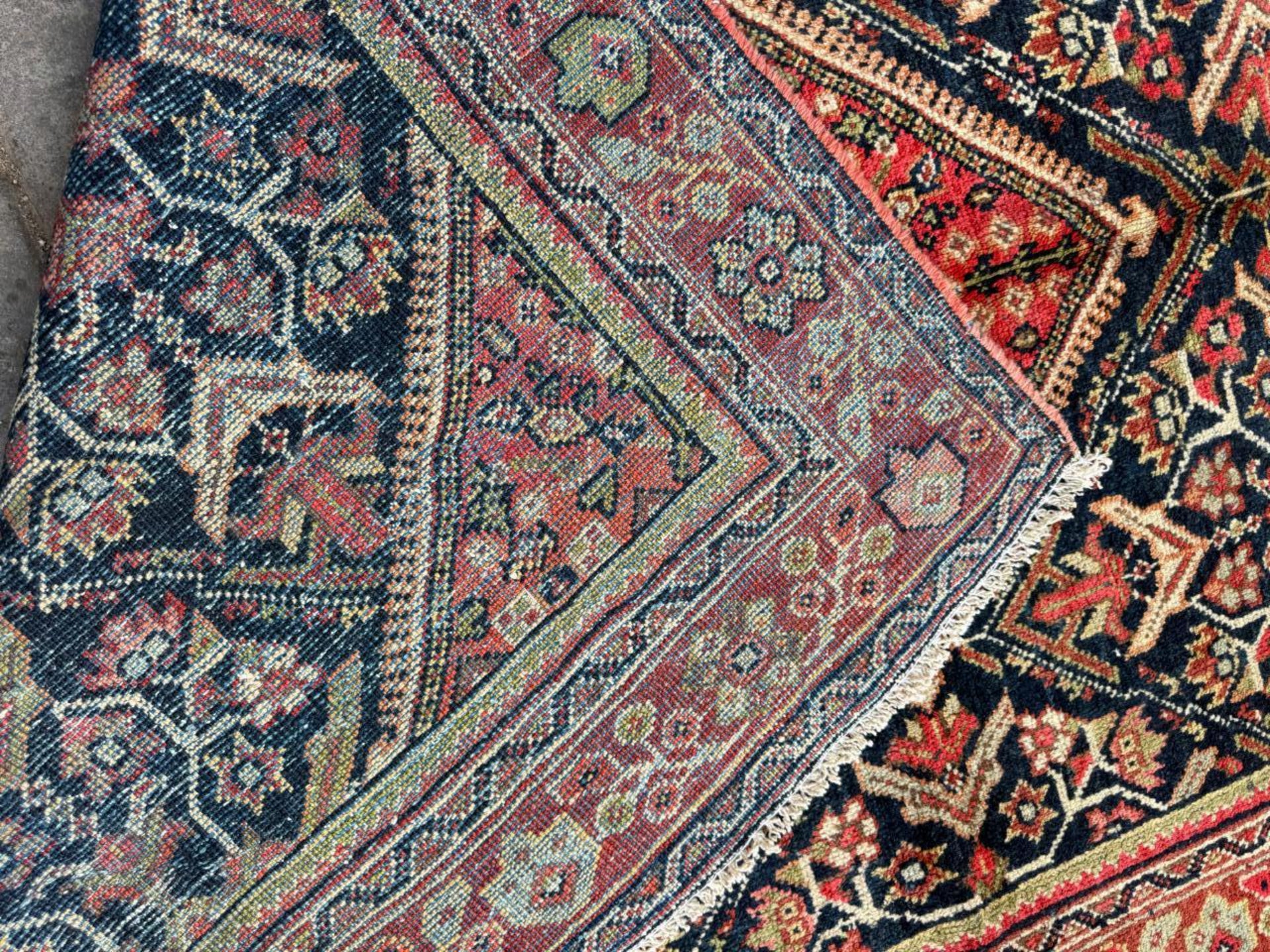 Detail of the rich terracotta red elements within the rug's design.


