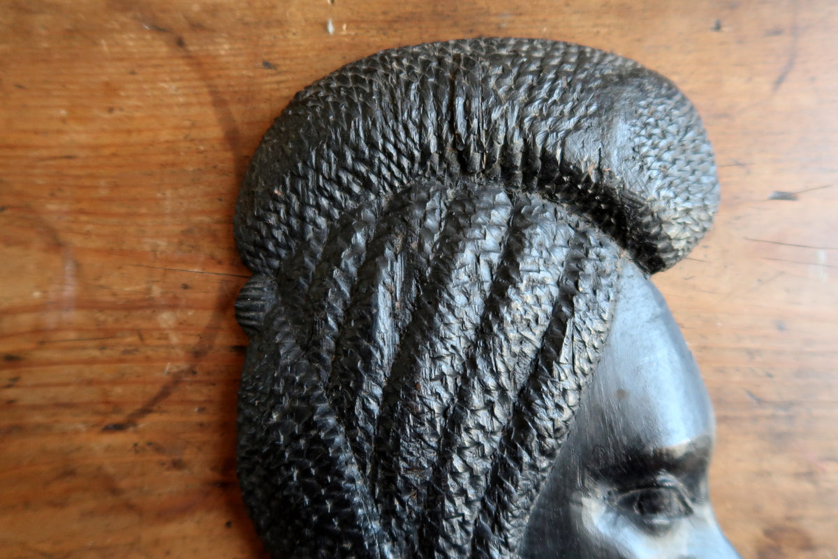 Dense timber grain and hand-tooled carving marks on an authentic Makonde style wooden wall plaque.