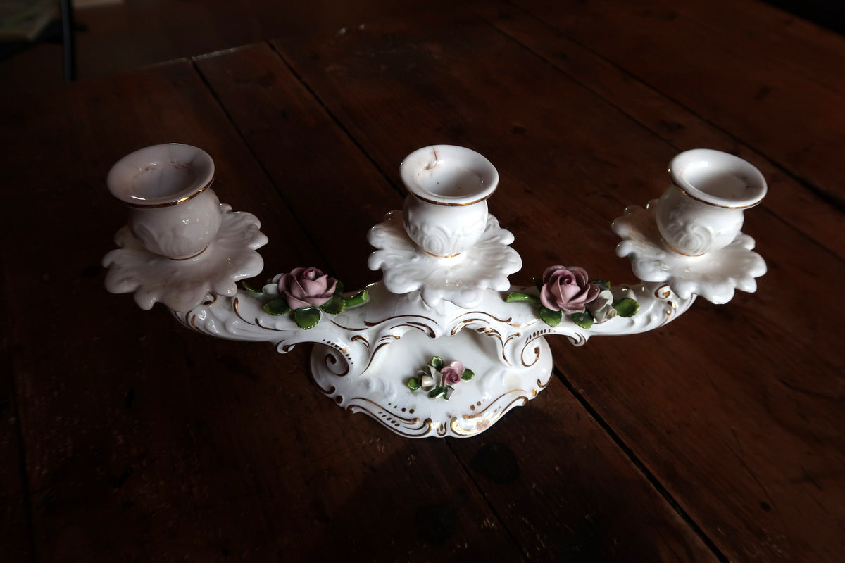 Fine German porcelain candlestick featuring three candle sockets, classical Rococo scrollwork, and delicate rose motifs.