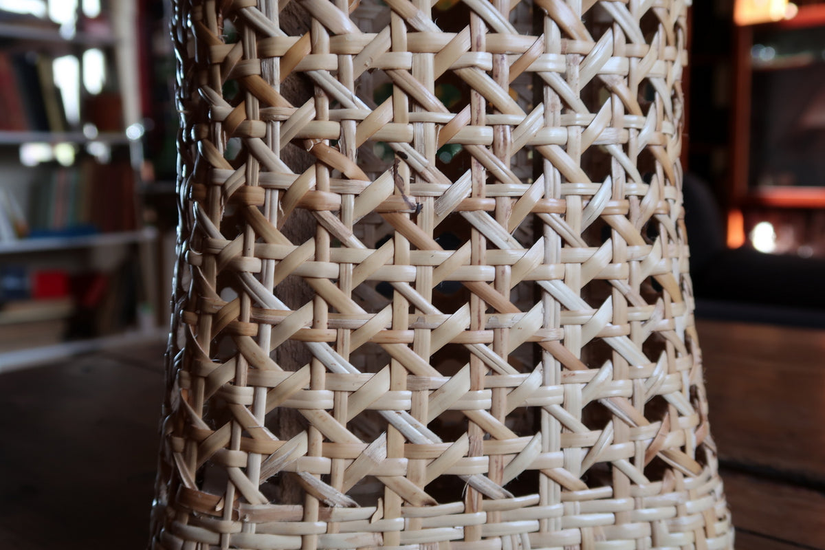 Detailed openwork Vienna straw weave lattice bounded by smooth bentwood rattan contours.