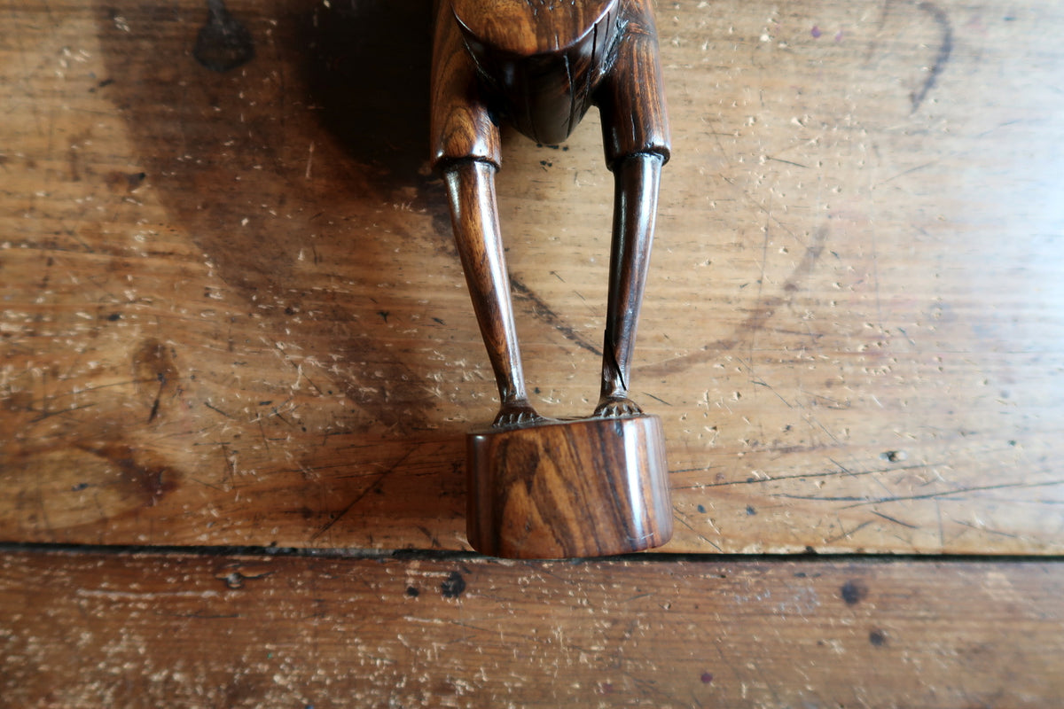 Carved muscular torso and structured posture on a vintage hand-carved African hardwood figure.