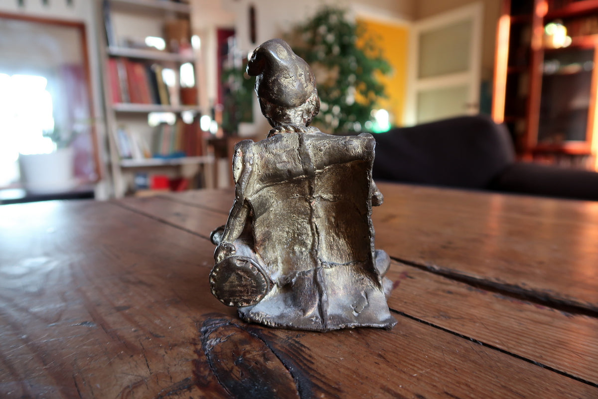 Warm golden brass patina and textured metal casting surfaces on a vintage West African collectible sculpture.