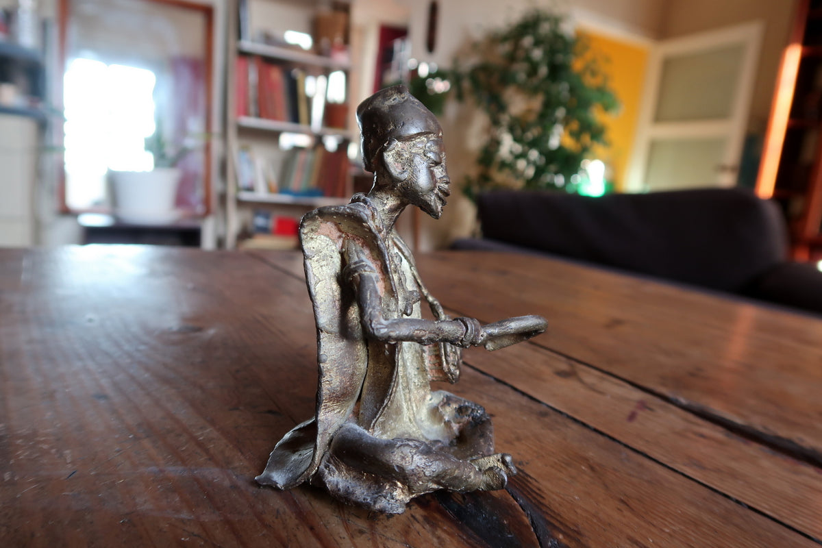 Hand-tooled surface details and traditional lost-wax casting texture on a West African brass figurine.